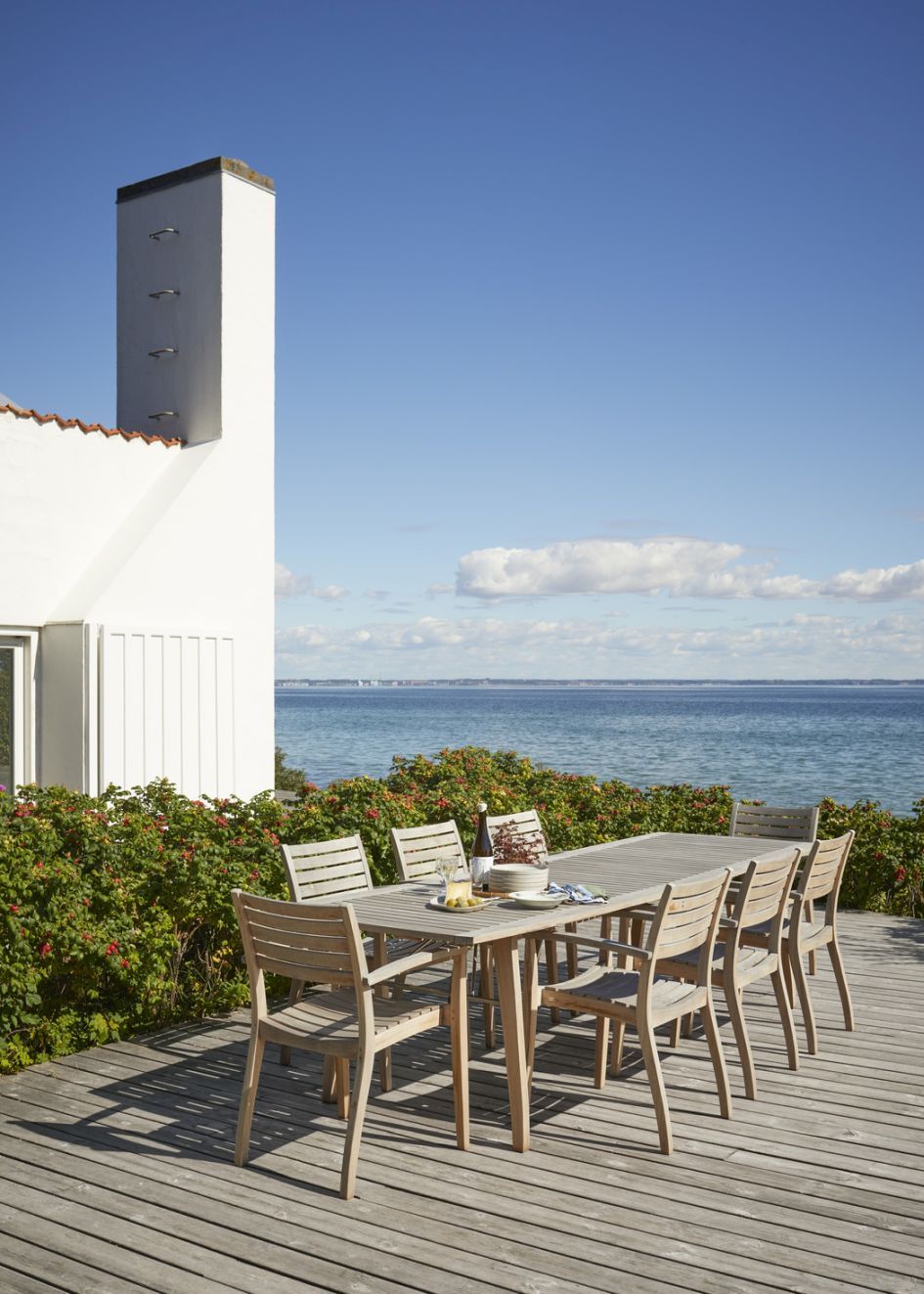 Ballare Tisch von Skagerak by Fritz Hansen: Outdoor Esstisch mit Stühlen auf Holzterrasse am Meer.