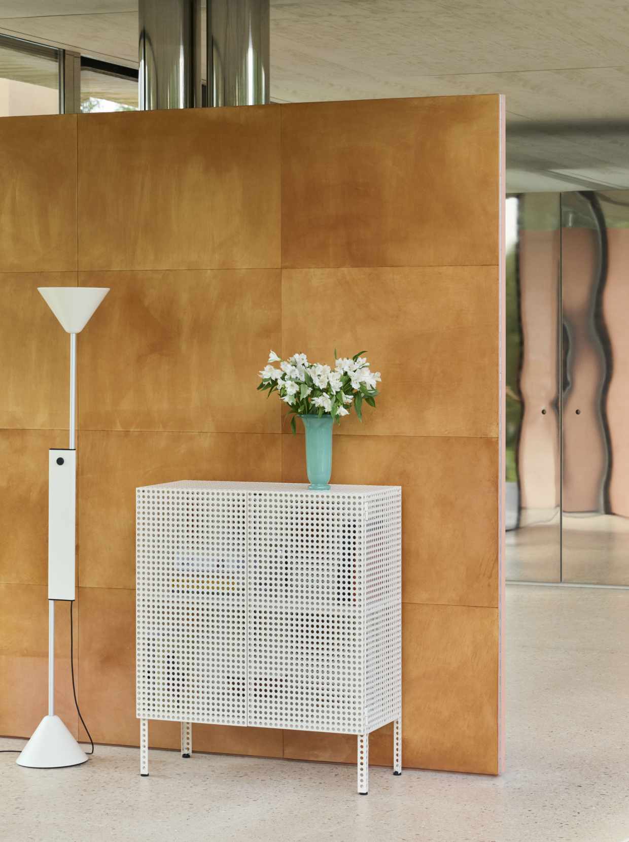 Weißes HAY Sideboard "Perforated Cabinet Floor Medium" mit Lochmuster und Blumen in modernem Interieur.
