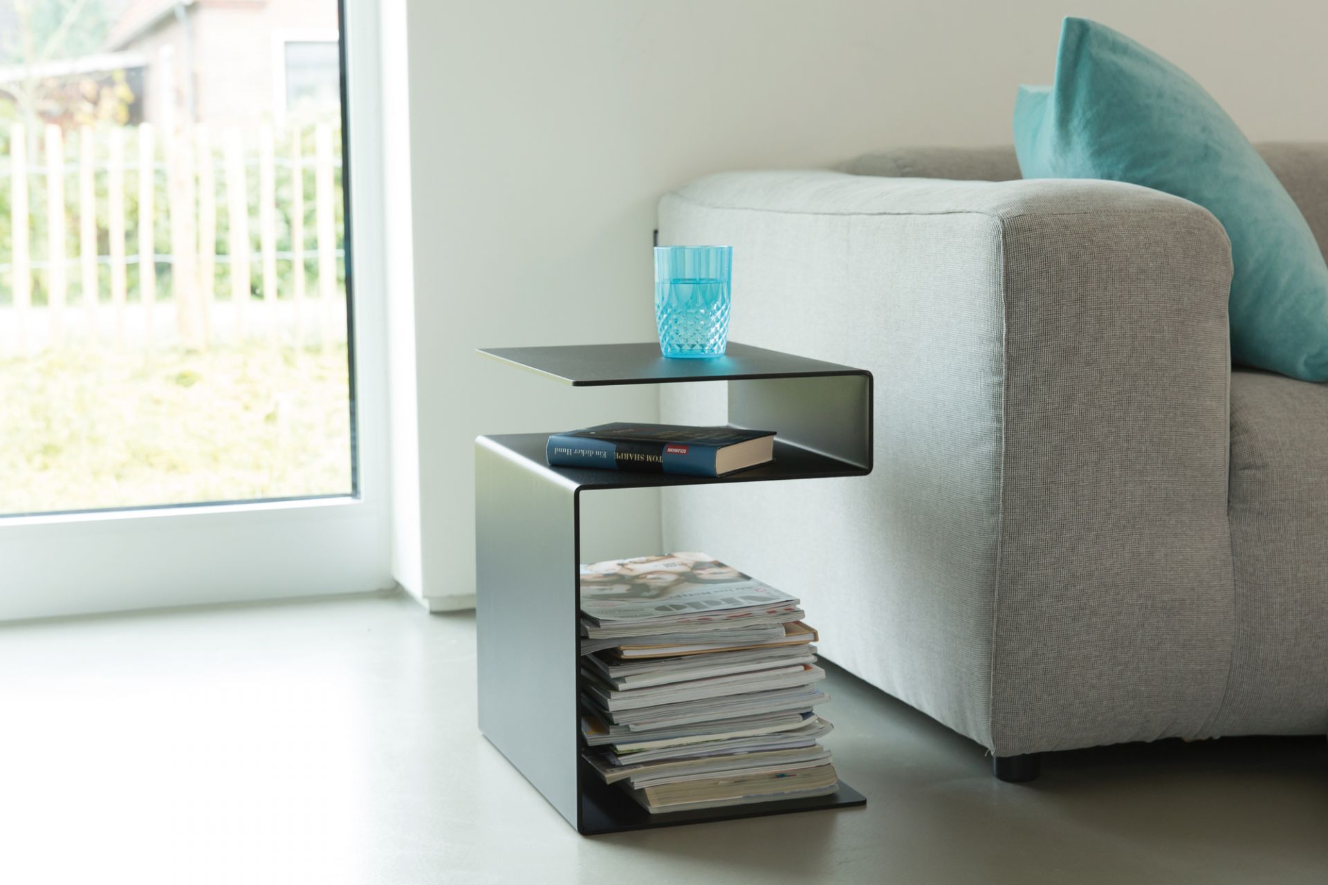 Huk Beistelltisch von Müller Möbelwerkstätten in Schwarz mit Glas Wasser, Buch und Zeitschriften.