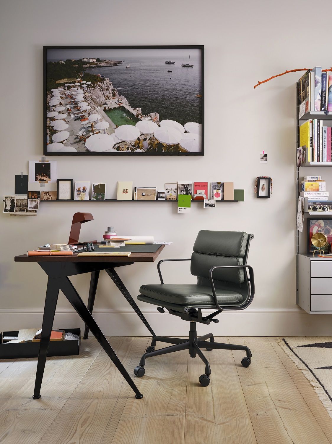 Büro mit Vitra Soft Pad Chair EA217 in Grünleder, Schreibtisch und Regalsystem im Hintergrund.