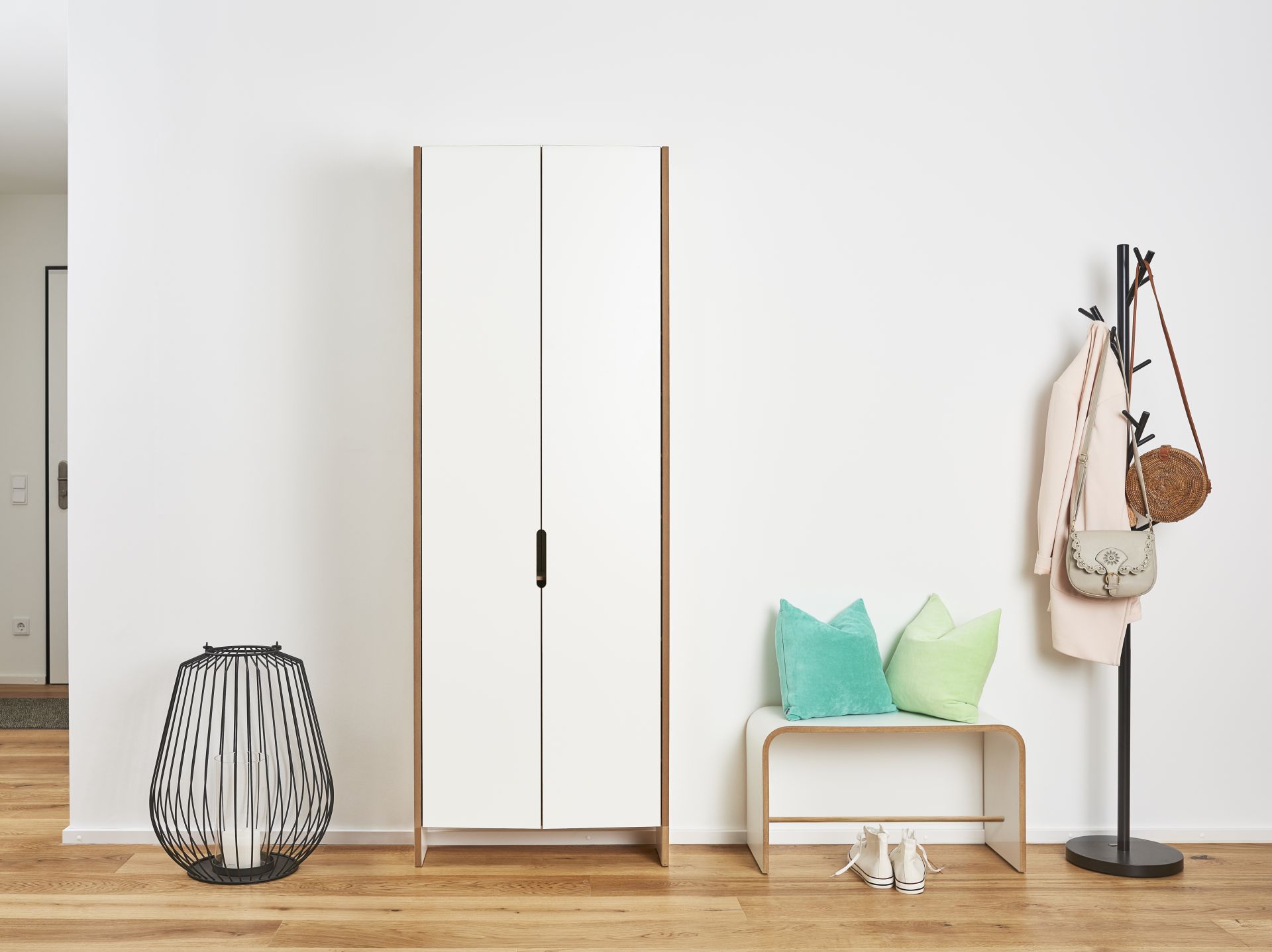 Heller Flur mit weißem Tojo Sit Hocker, Garderobe, Schrank, Dekoration und Holzboden für ein modernes Zuhause.