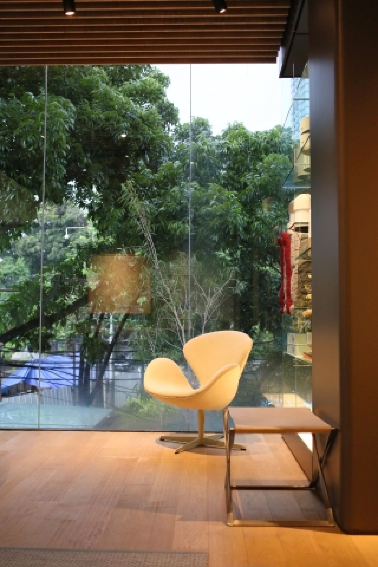 Beiger Schwanensessel von Fritz Hansen mit PK91 Falthocker im modernen Wohnzimmer mit Blick ins Grüne.