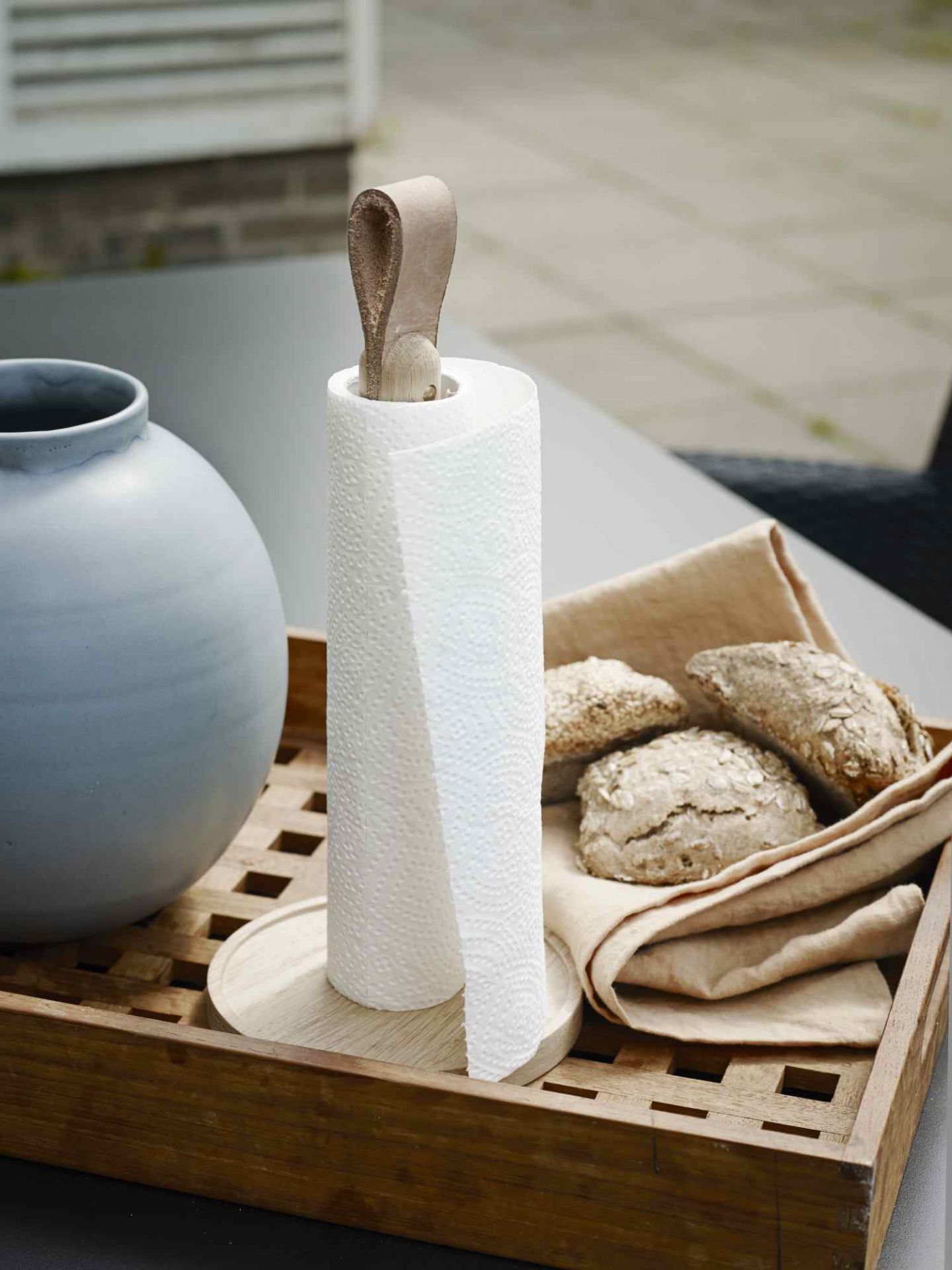 Norr Küchenrollenhalter von Skagerak: Küchenrolle auf Holztablett mit Brötchen und Vase.