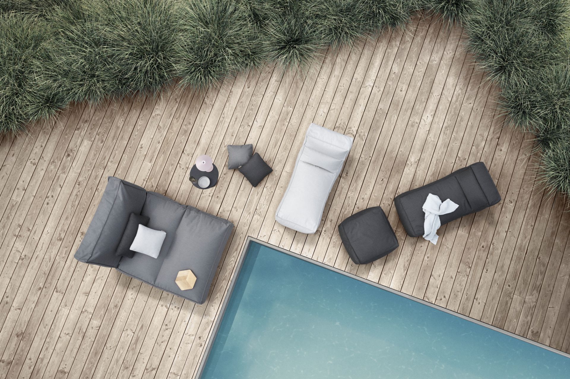 Draufsicht: Blomus STAY Outdoor Kissen und Loungemöbel in Grau und Weiß auf Holzdeck neben Pool.