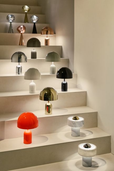 Vielfalt an Tom Dixon Bell LED Tischleuchten in Gold, Rot, Schwarz und Marmor auf Treppe.
