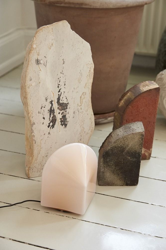Nahaufnahme der Parade Table Lamp Tischleuchte von Hay, rosa, auf weißem Holzboden mit Dekoration.