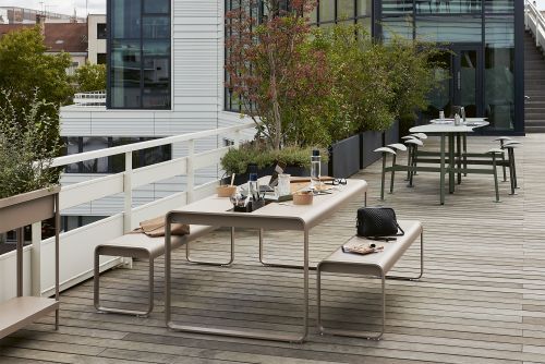 Bolder 2-Sitzer Tisch mit Sitzflächen von Fermob für den Outdoor-Bereich auf einer Dachterrasse.