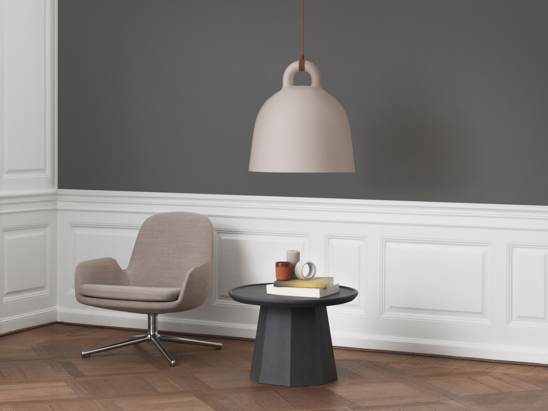 Normann Copenhagen Pine Table Large Beistelltisch in dunklem Holz, kombiniert mit Design-Sessel und Pendelleuchte.