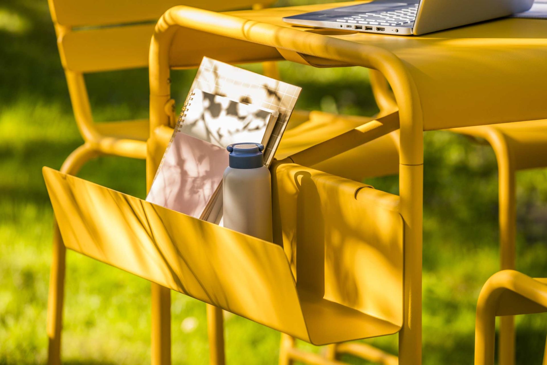 Gelber Luxembourg Work Stehtisch von Fermo im Freien mit Laptop, Notizbuch und Trinkflasche.