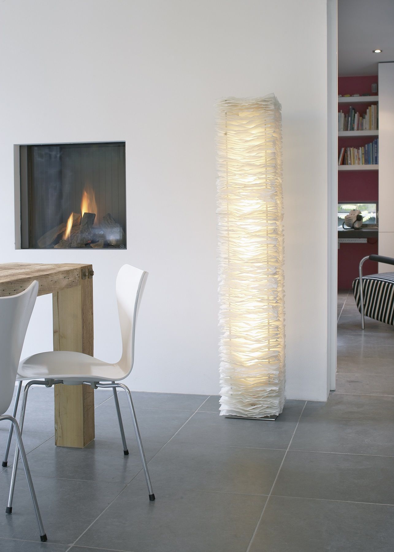 Moderne Stehleuchte aus Papier in weißem Wohnzimmer mit Kamin und Holztisch für gemütliche Atmosphäre.