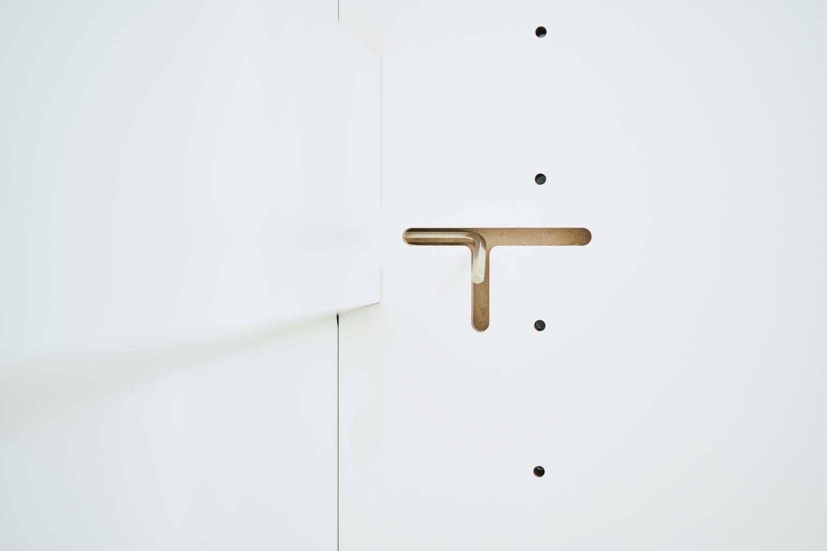 Detailaufnahme des Tojo-Schrank Anbaumoduls: Weiße Schrankwand mit Aussparung für die Verbindung mit anderen Modulen.