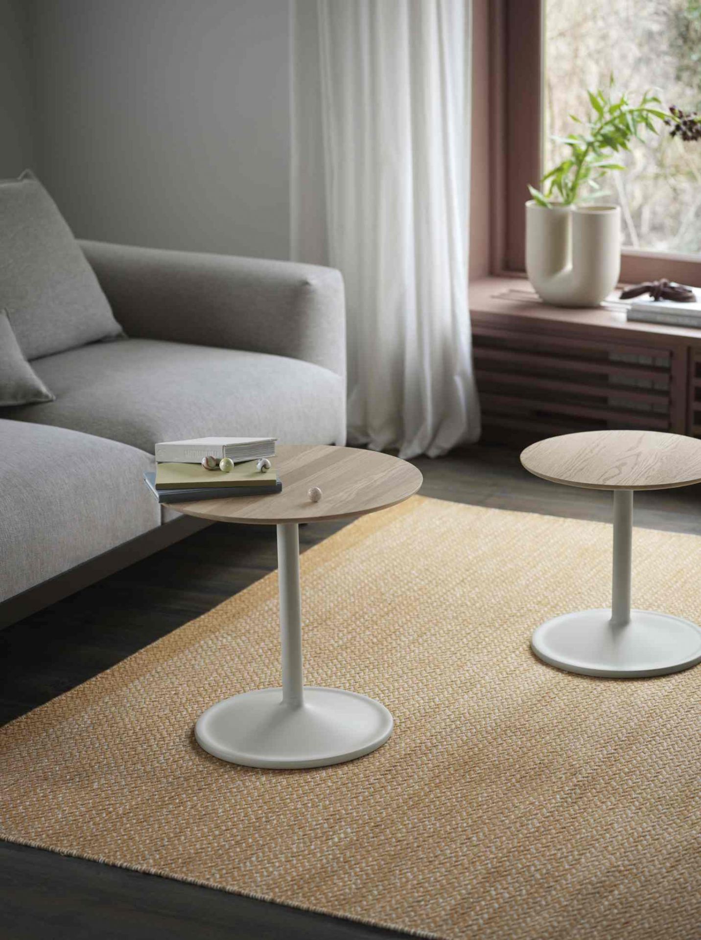 Zwei runde Beistelltische, einer davon ein Muuto Soft Side Table, im Wohnzimmer neben einem Sofa.