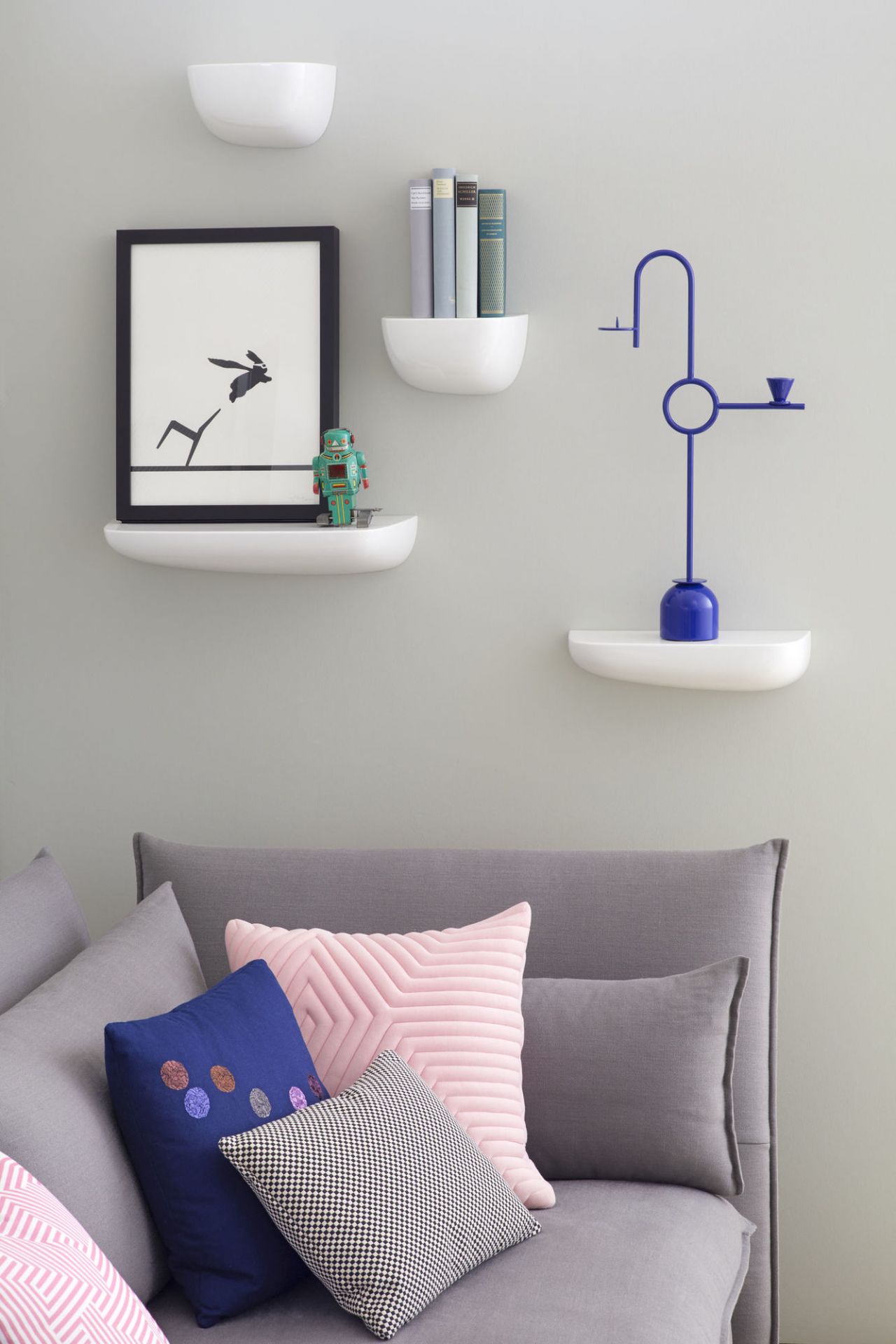 Wanddekoration mit weißen Corniches Wandboards von Vitra, dekoriert mit Kunst, Büchern und einer blauen Skulptur.