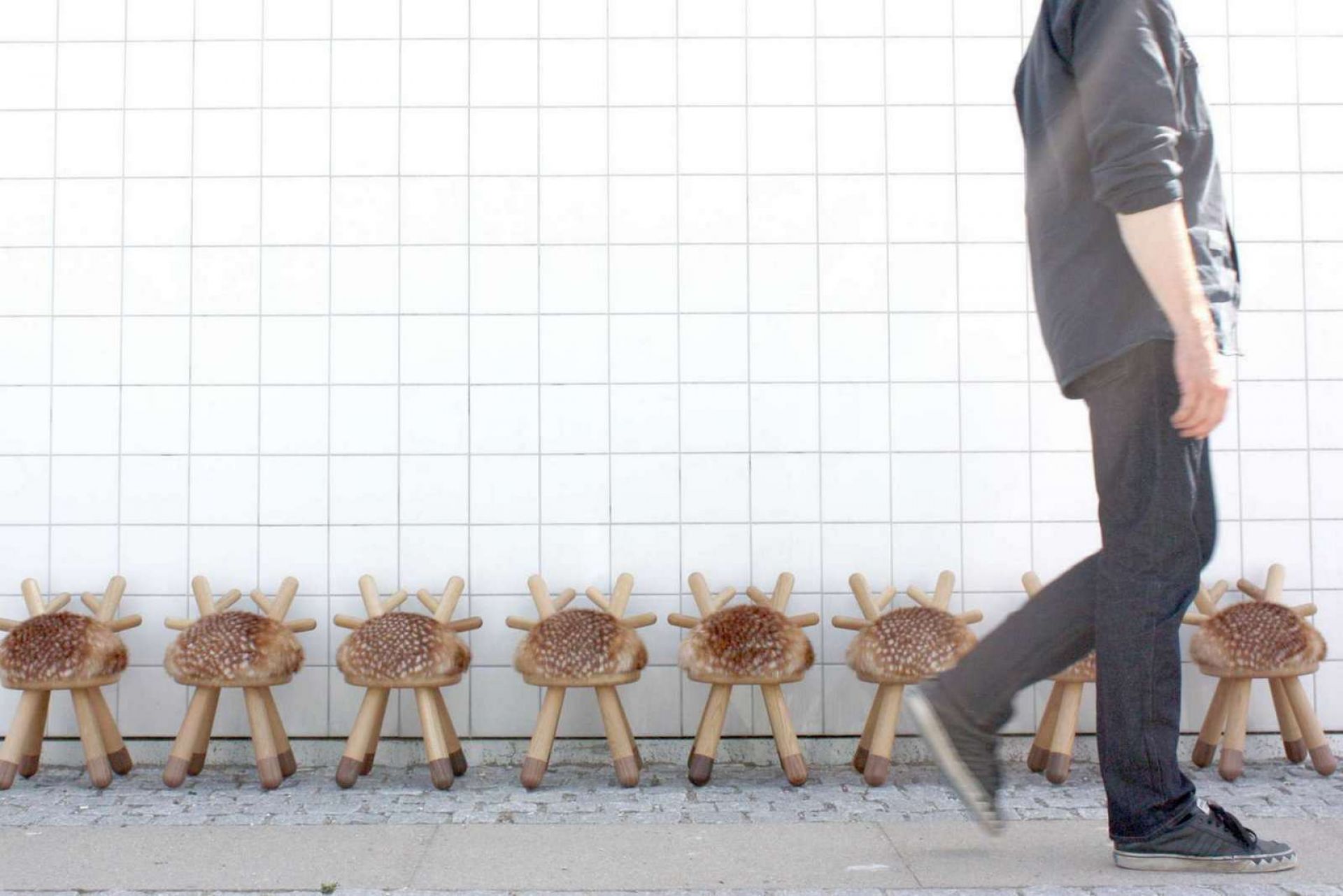 Reihe von Bambi Chair Kinderstühlen von EO  aus Holz mit Fellimitat vor weißer Wand.