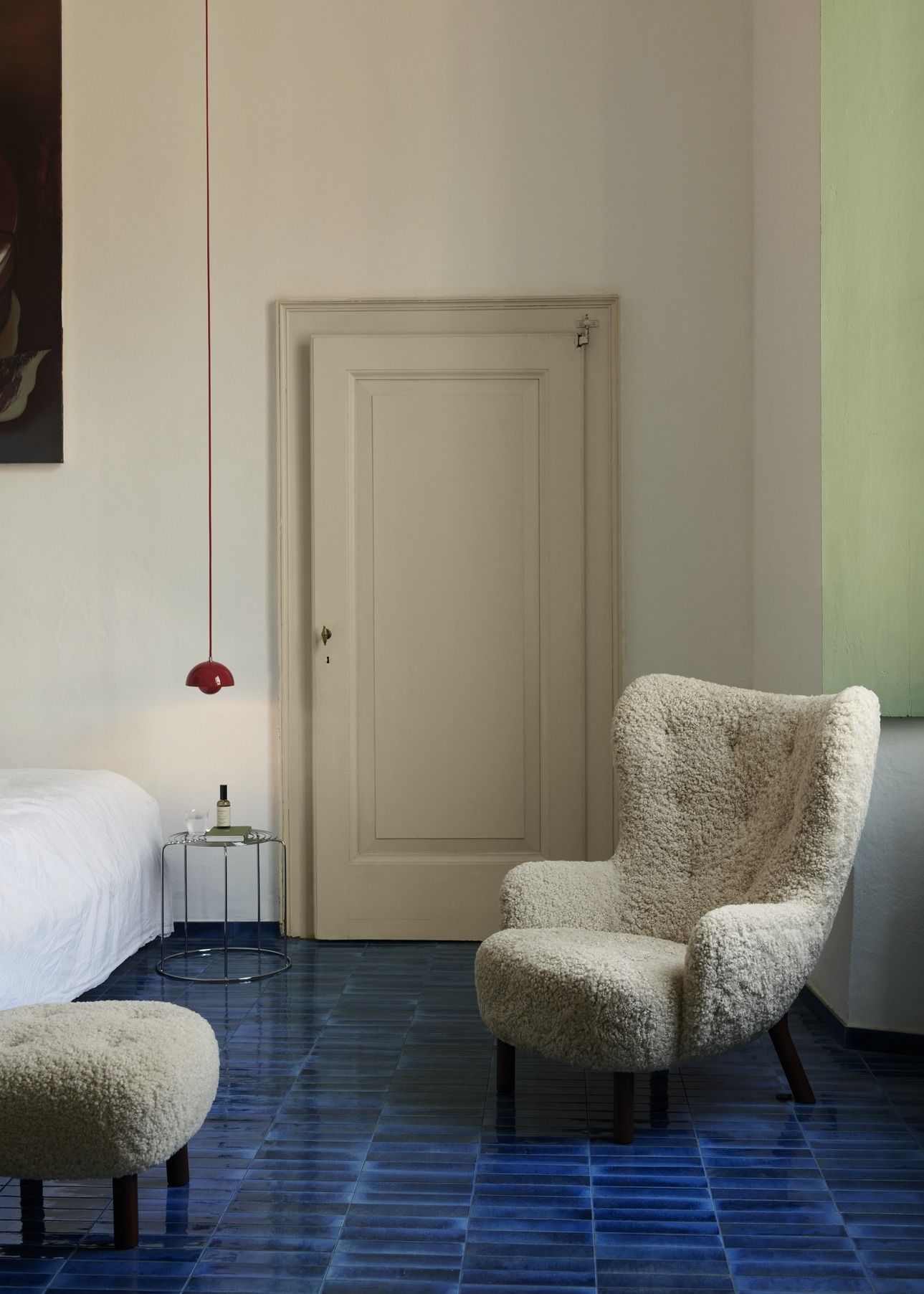 AndTradition Wire Stool VP11 als Beistelltisch im Schlafzimmer mit Sessel und blauen Fliesen.