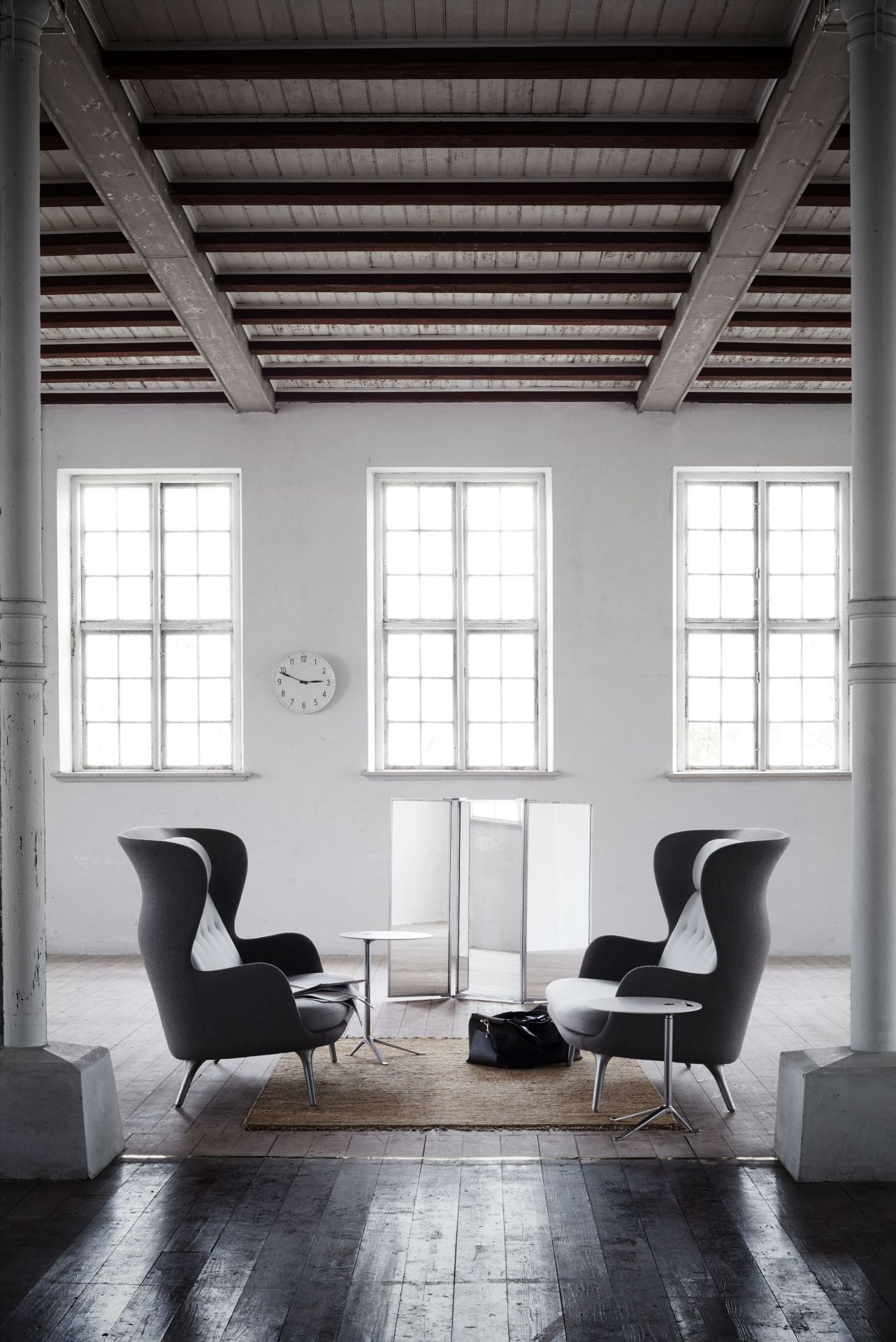 Zwei graue Fritz Hansen Ro Sessel aus Holz mit Beistelltischen in einem hellen Raum.
