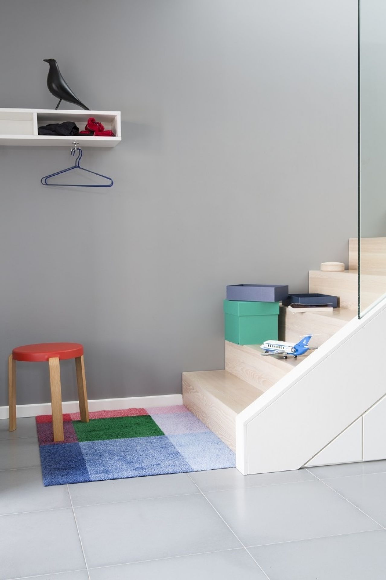 Heymat Fußmatte Mix Indoor/Outdoor mit farbenfrohem Design im Eingangsbereich eines modernen Hauses, neben Treppe und Hocker.