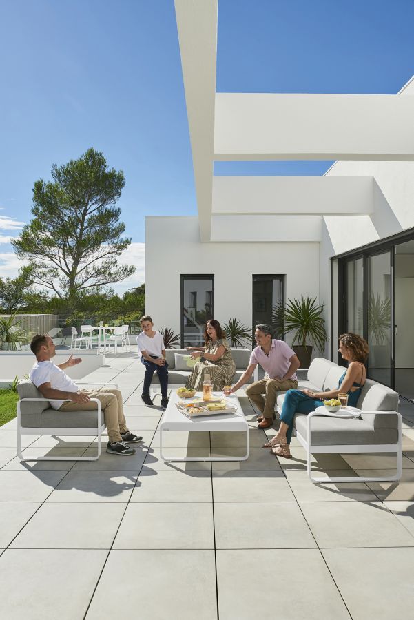 Familie entspannt am Bellevie Outdoor Tisch von Fermob auf einer modernen Terrasse.