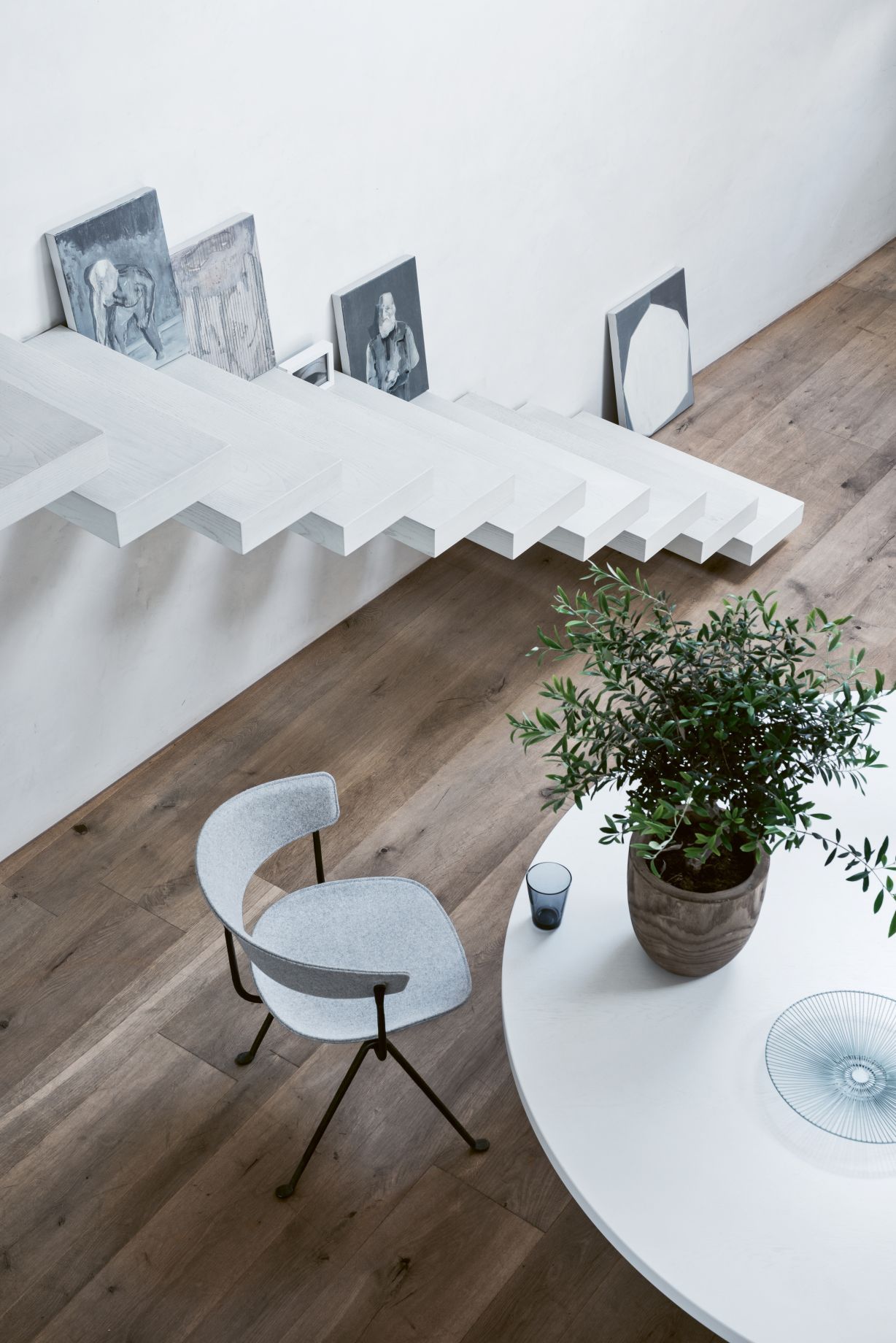 Grauer Officina Stuhl von Magis neben einem weißen Tisch mit Pflanze und Dekoration.