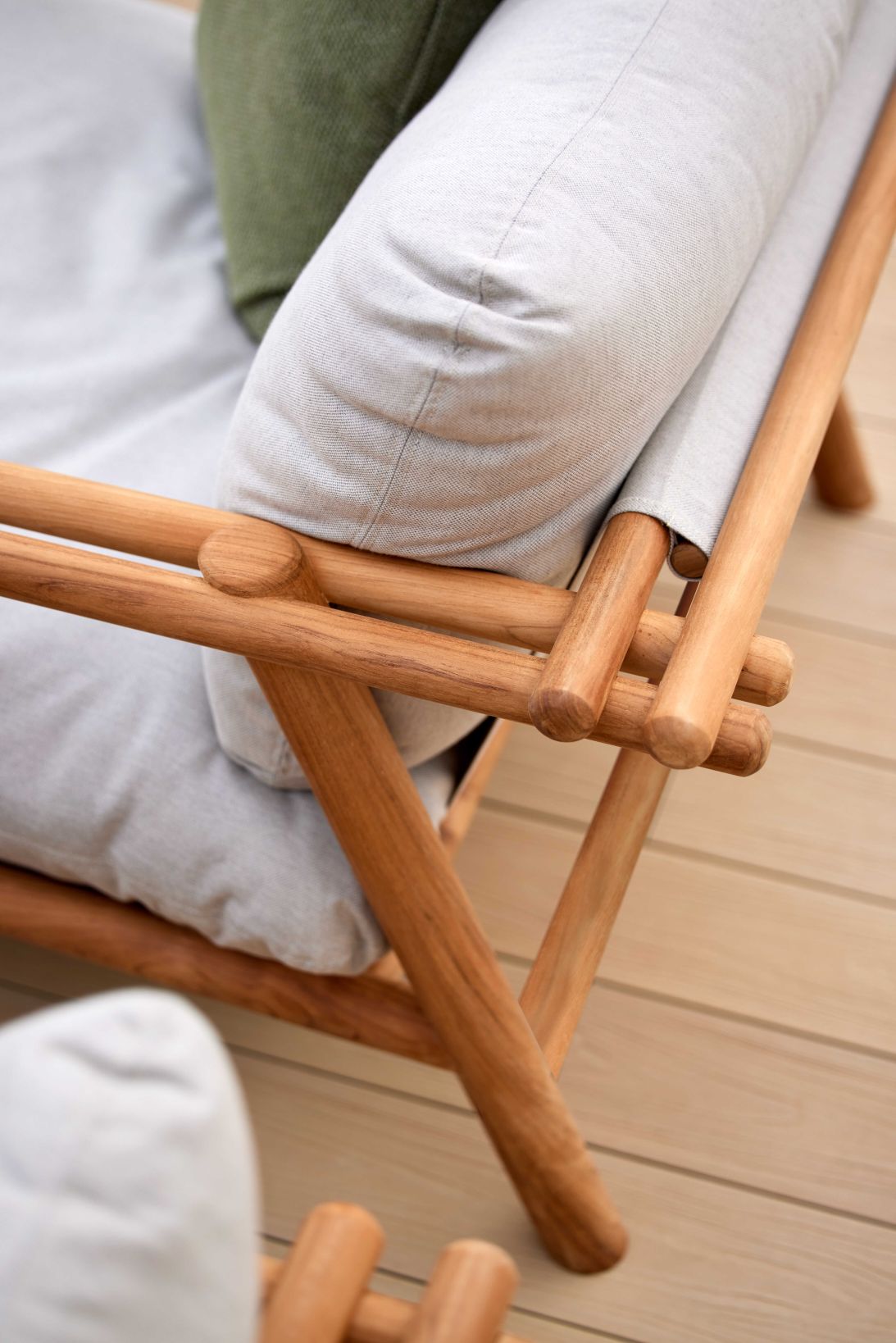 Detailaufnahme des Cane-Line Sticks Outdoor Loungesessels aus Teakholz mit hellgrauen Kissen.