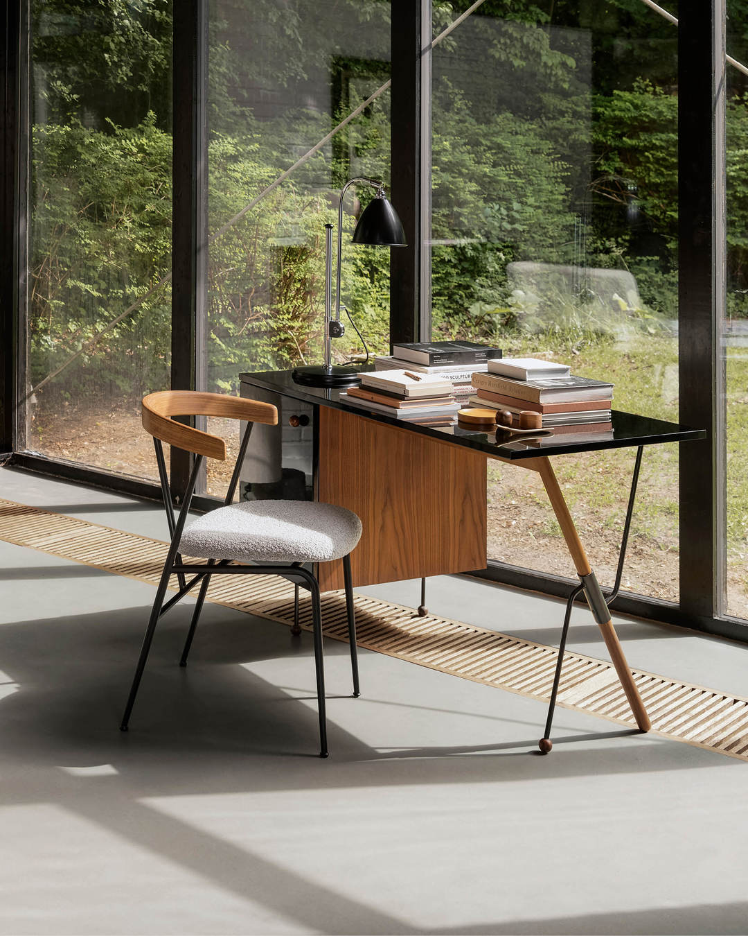 Gubi 62 Desk Schreibtisch mit schwarzer Glasplatte, Holzkorpus und passendem Stuhl vor Fensterfront.