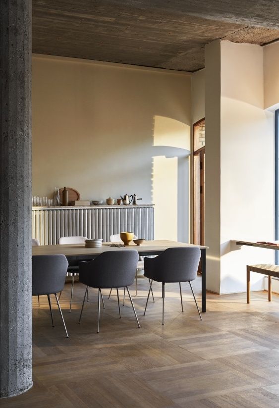 AndTradition Drip Table HW58 Esstisch mit Stühlen in modernem Esszimmer mit Holzboden und Betonpfeiler.