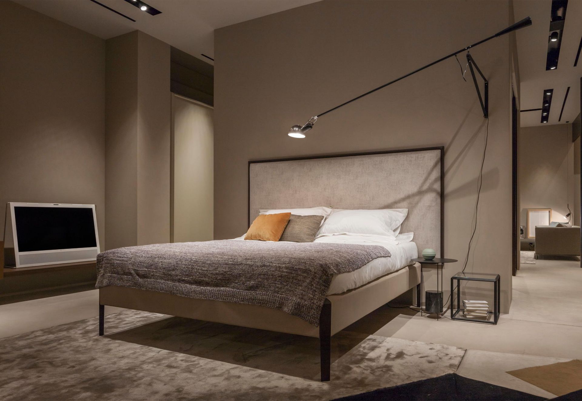 Schlafzimmer mit Bett und schwarzer Flos 265 Wandleuchte für indirekte Beleuchtung über dem Nachttisch.