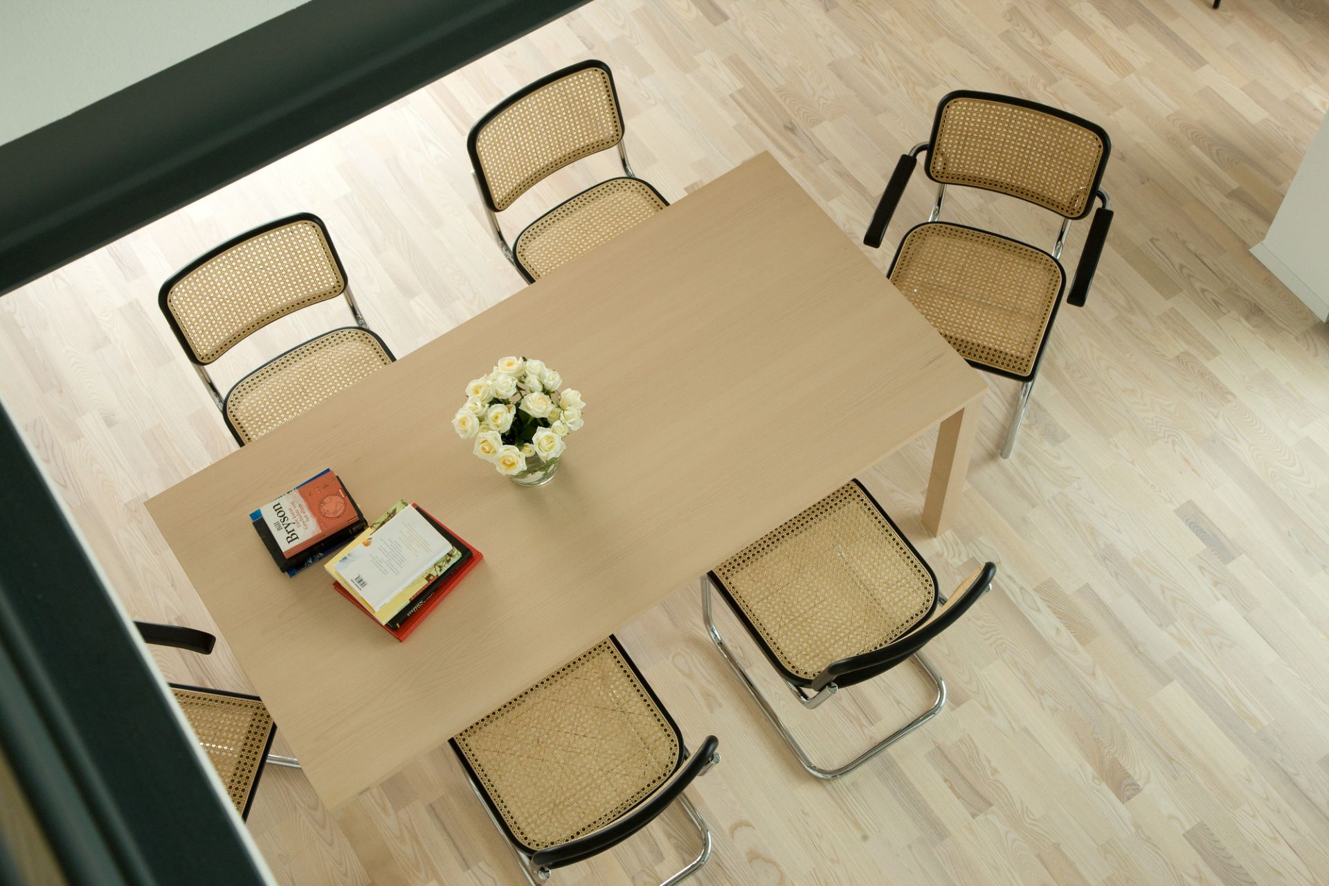 S 64 Freischwinger Stühle von Thonet um einen Esstisch mit Blumen und Büchern, Vogelperspektive.