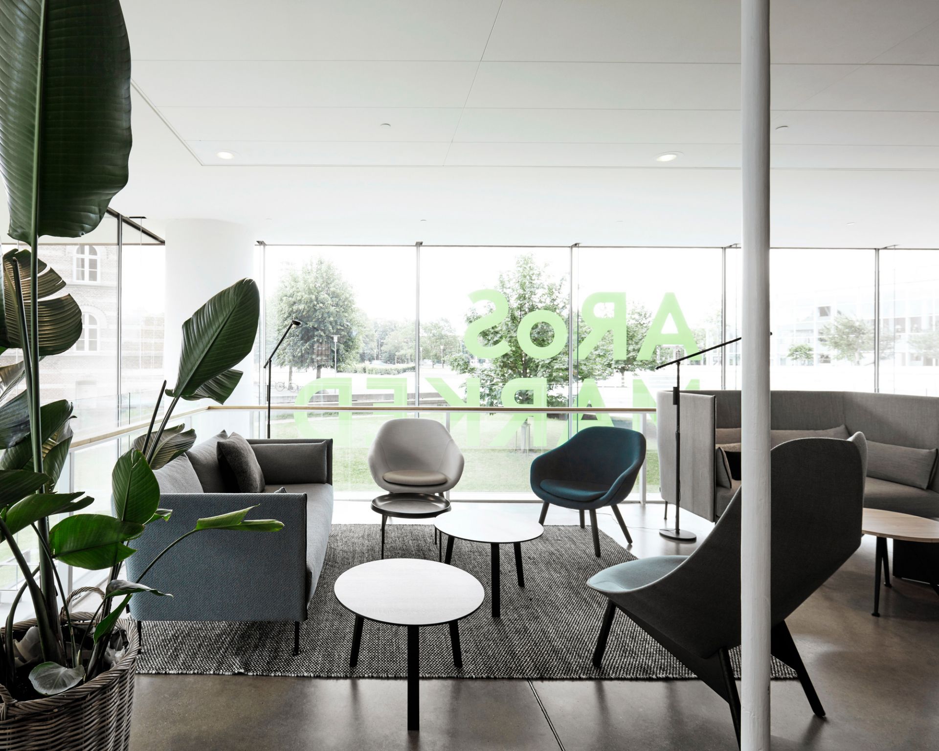 Heller Raum mit Hay About a Lounge AAL 82 Sesseln und Sofas in Grau- und Blautönen.