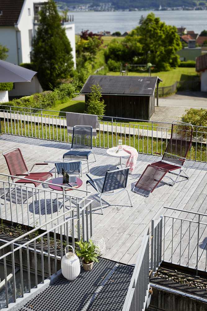 Altorfer Lounge Sessel Outdoor: Hellblauer Gartensessel und weitere Gartenmöbel auf einer Terrasse mit Blick ins Grüne.