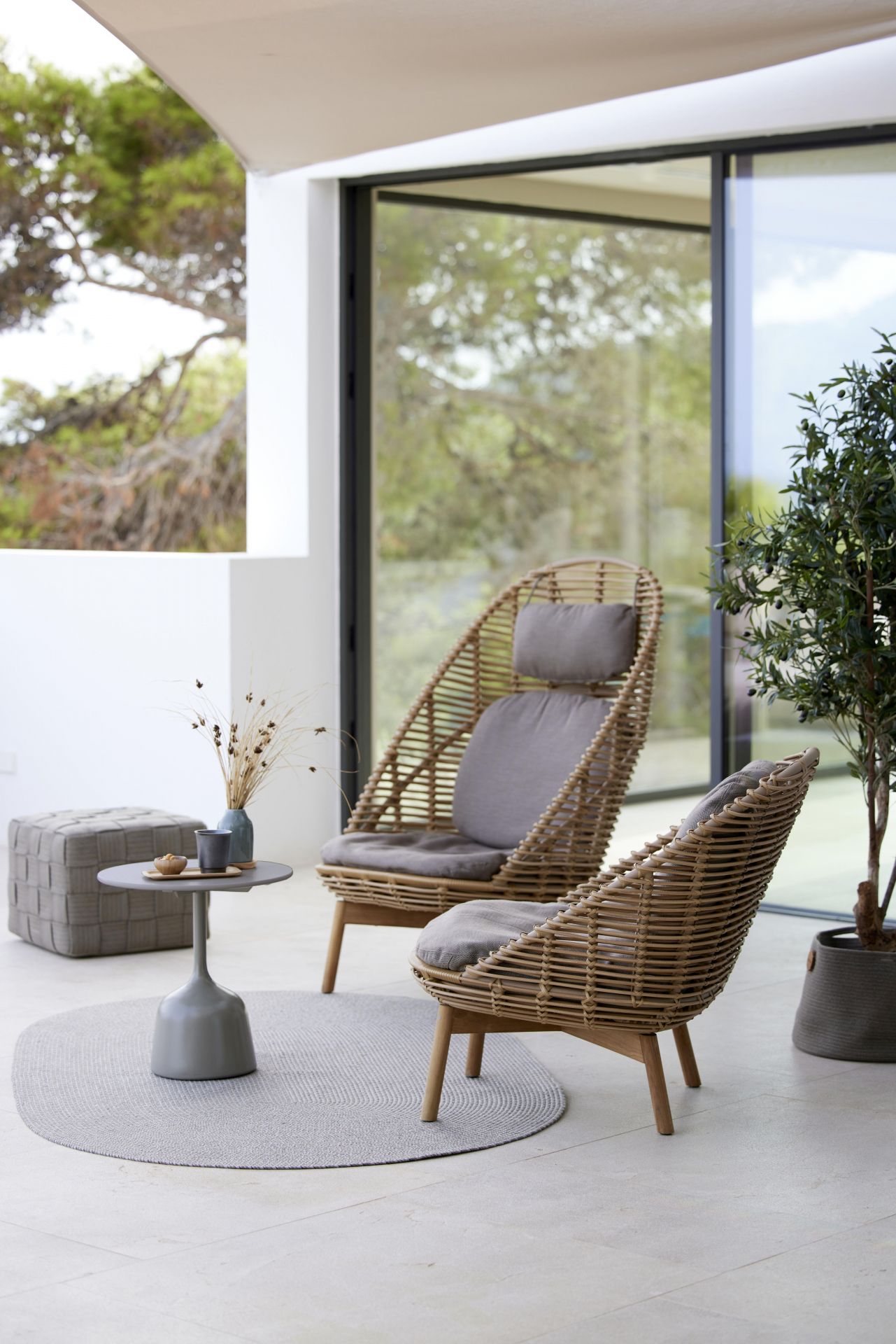 Zwei Cane-Line Highback Sessel aus Rattan mit Teakholzbeinen und grauen Kissen.