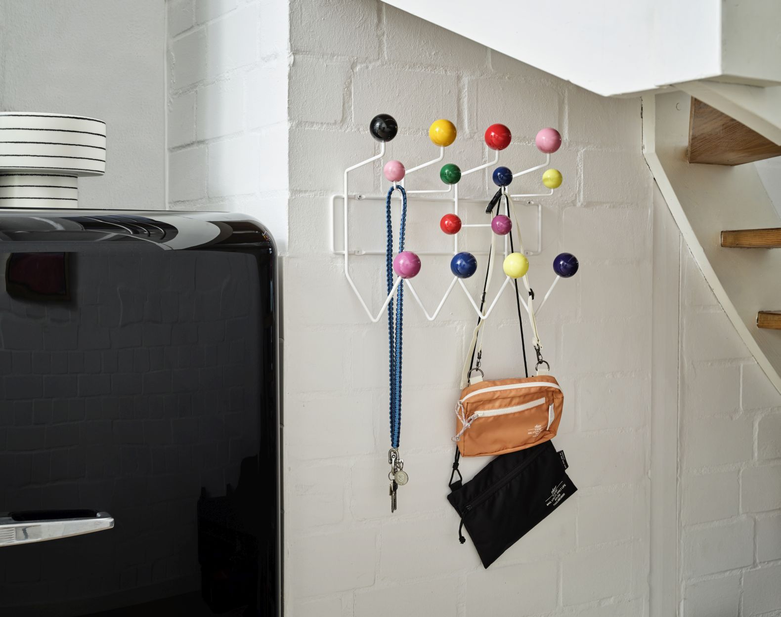 Eames Hang it all Garderobe von Vitra mit bunten Kugeln an weißer Wand, Taschen und Schlüssel.