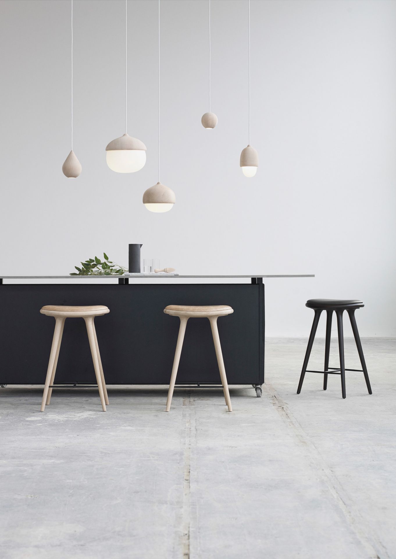 Innenaufnahme mit Liuku Base Ball Linde Pendelleuchten und Holzstühlen an einer Küchentheke.