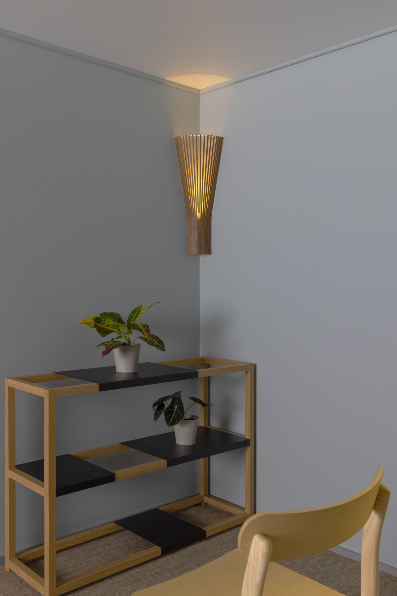 Secto 4236 Eckleuchte: Moderne Wandlampe aus Holz, die warmes Licht in einer Ecke erzeugt.