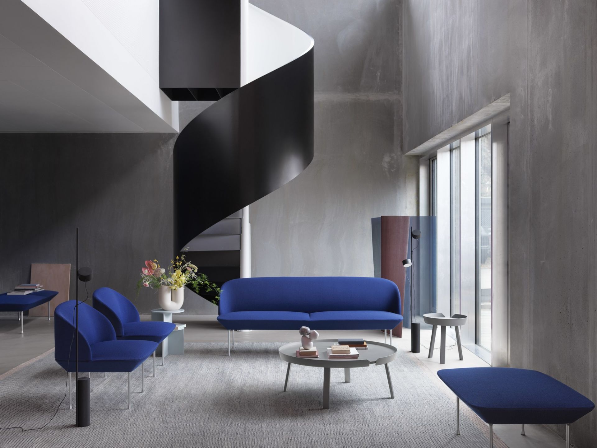 Blaues Oslo Sofa von Muuto in modernem Wohnzimmer mit Designermöbeln und Wendeltreppe.