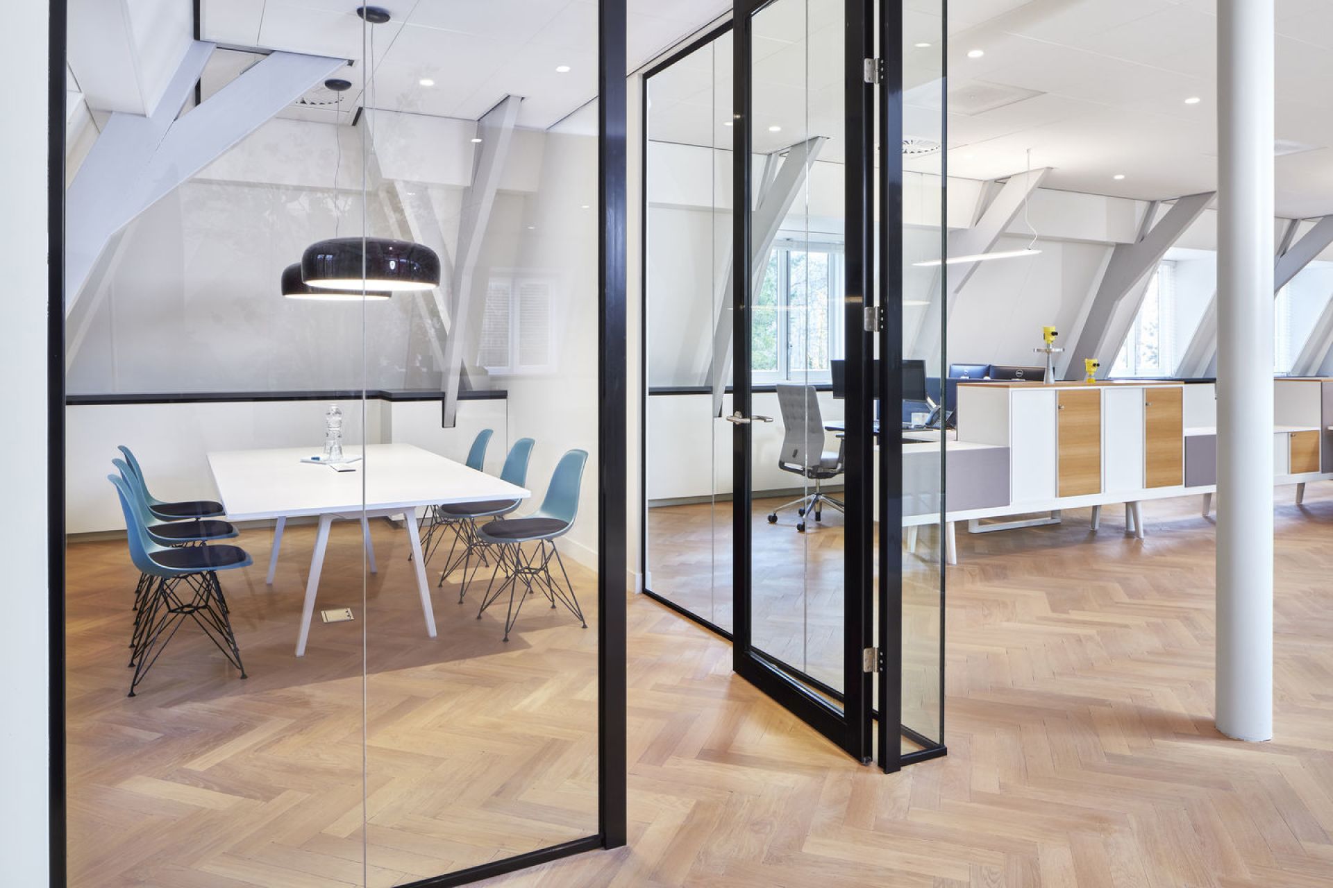 Eames DSR Stühle von Vitra in einem modernen Konferenzraum mit Glastüren und Parkettboden.