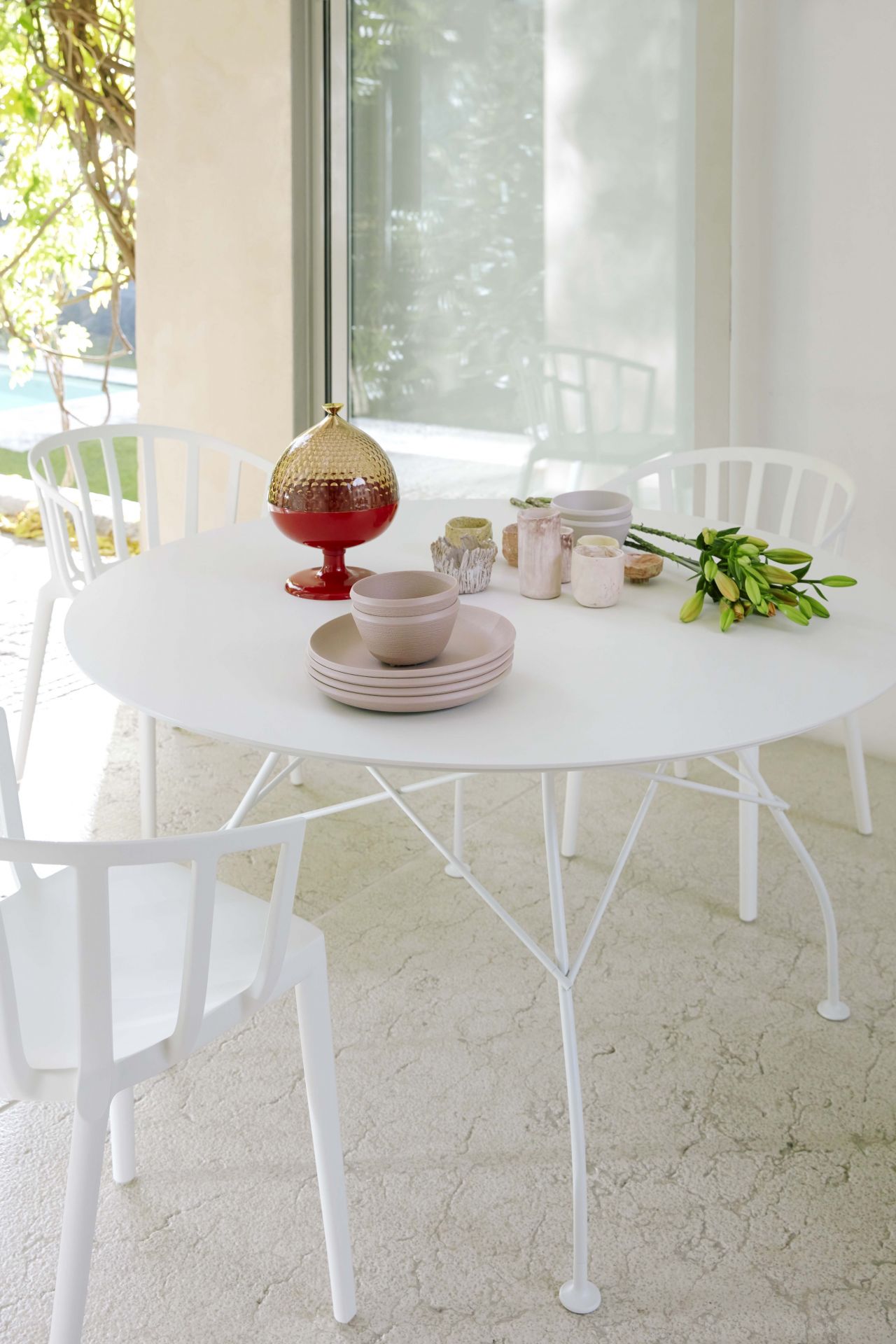 Runder, weißer Esstisch im modernen Design mit Geschirr und Dekoration. Kartell Tisch inspiriert.