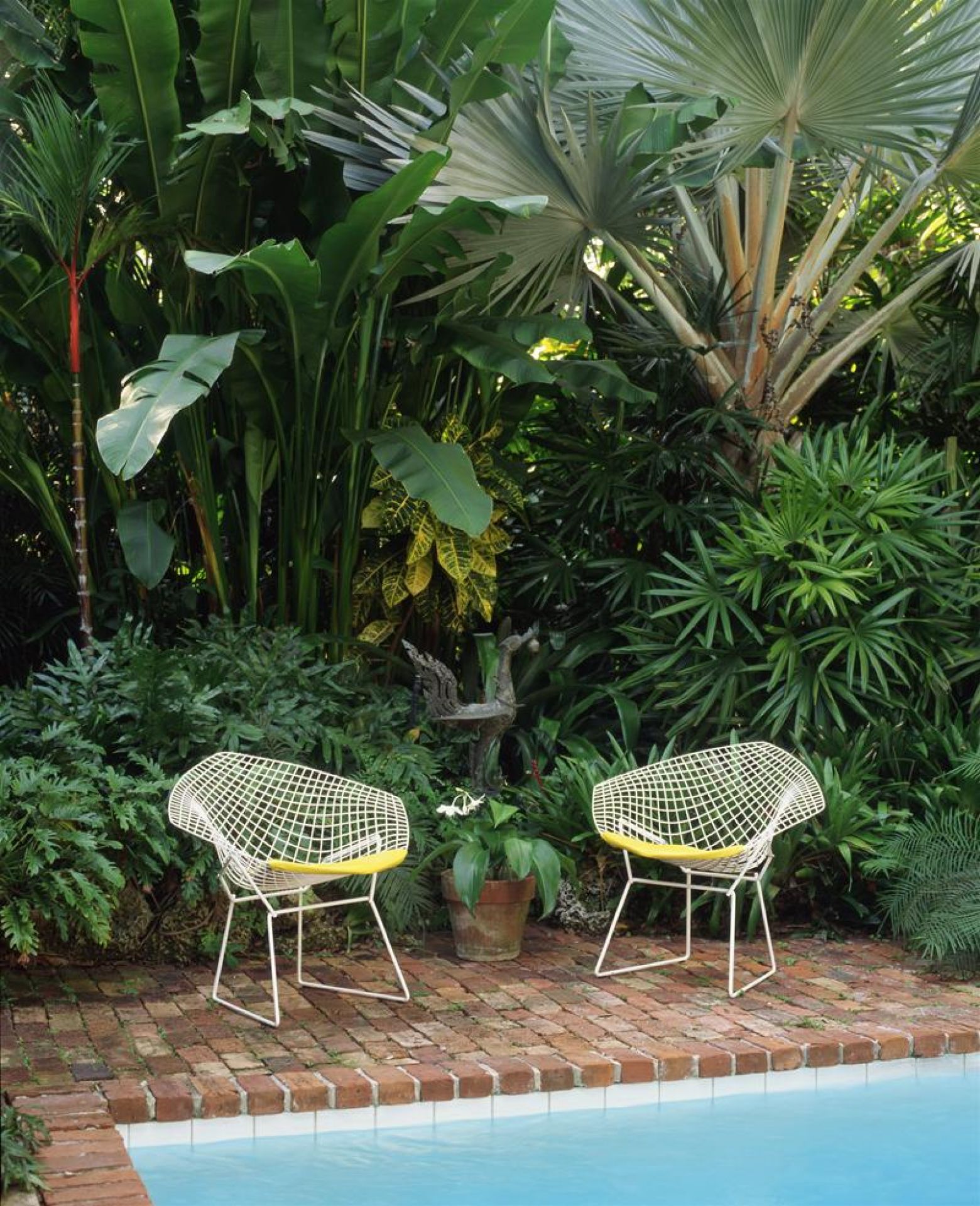 Zwei Bertoia Diamond Sessel Outdoor von Knoll International mit gelben Kissen am Pool.