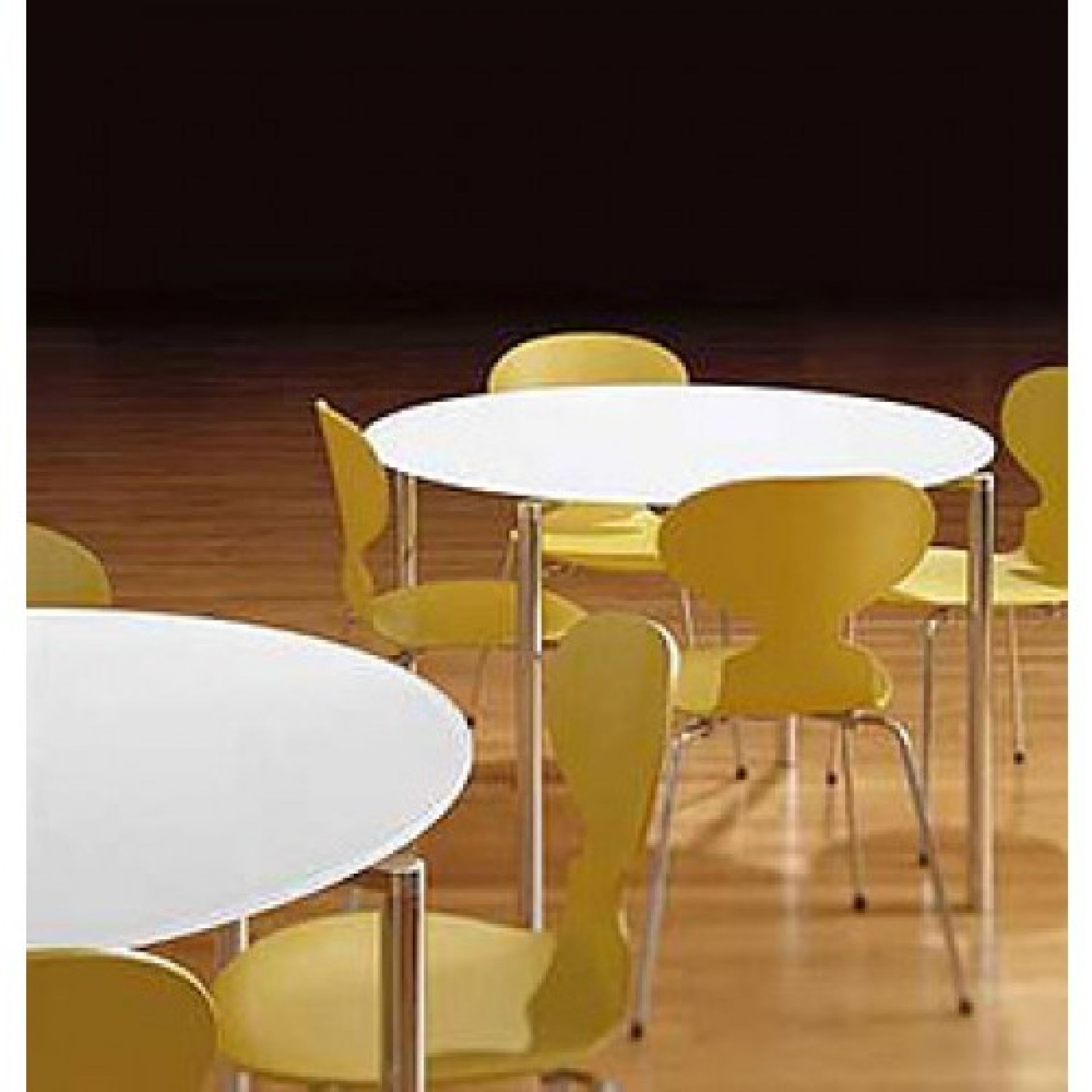Gelbe Ameise Stühle von Fritz Hansen mit drei Beinen um einen runden, weißen Tisch.