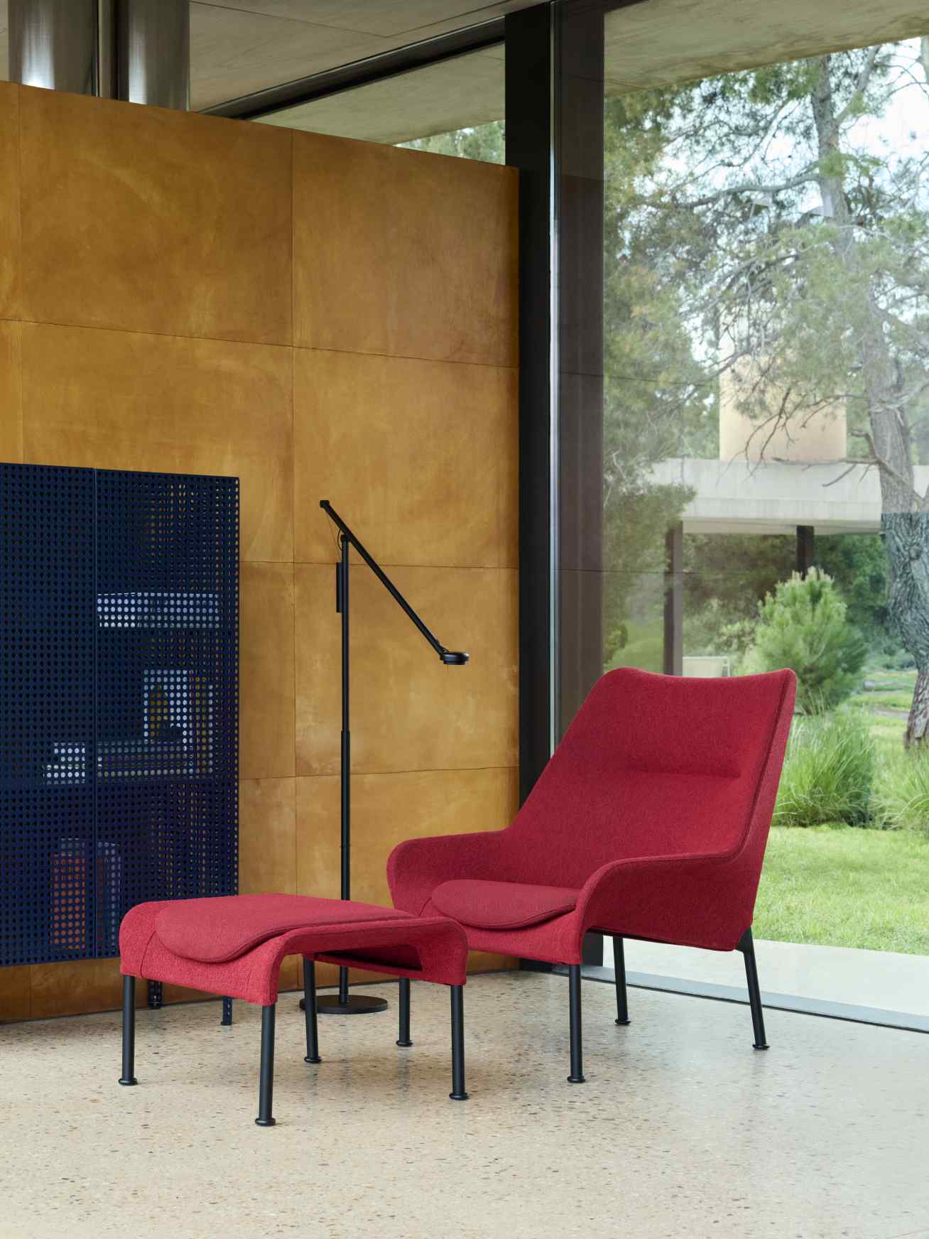 Roter Sessel mit Fußhocker und Hay Perforated Cabinet im modernen Wohnzimmer mit großem Fenster.