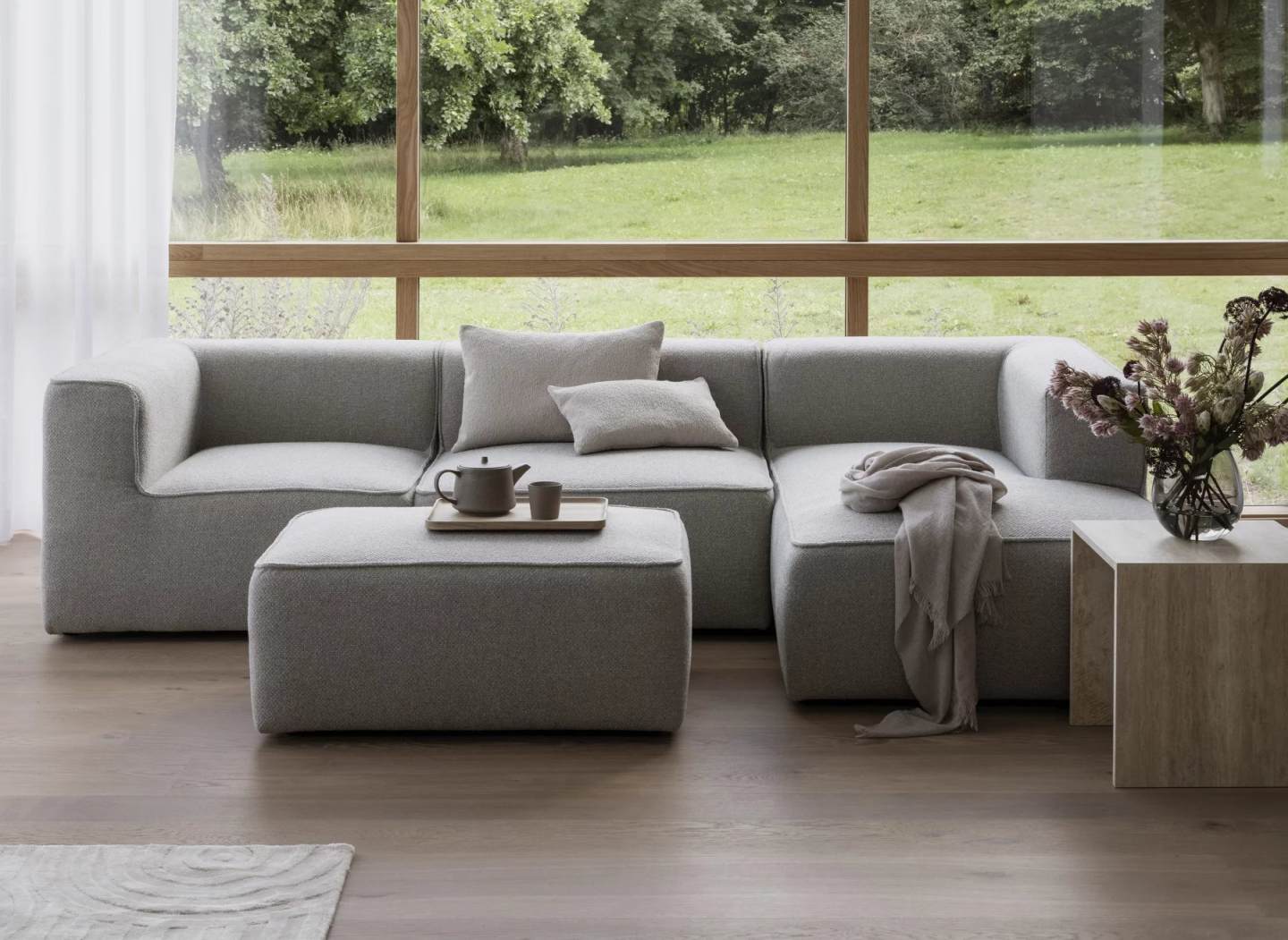 Varu Beistelltisch 2er Set von Blomus in Tundra Gray neben grauer Couch und Fenster.