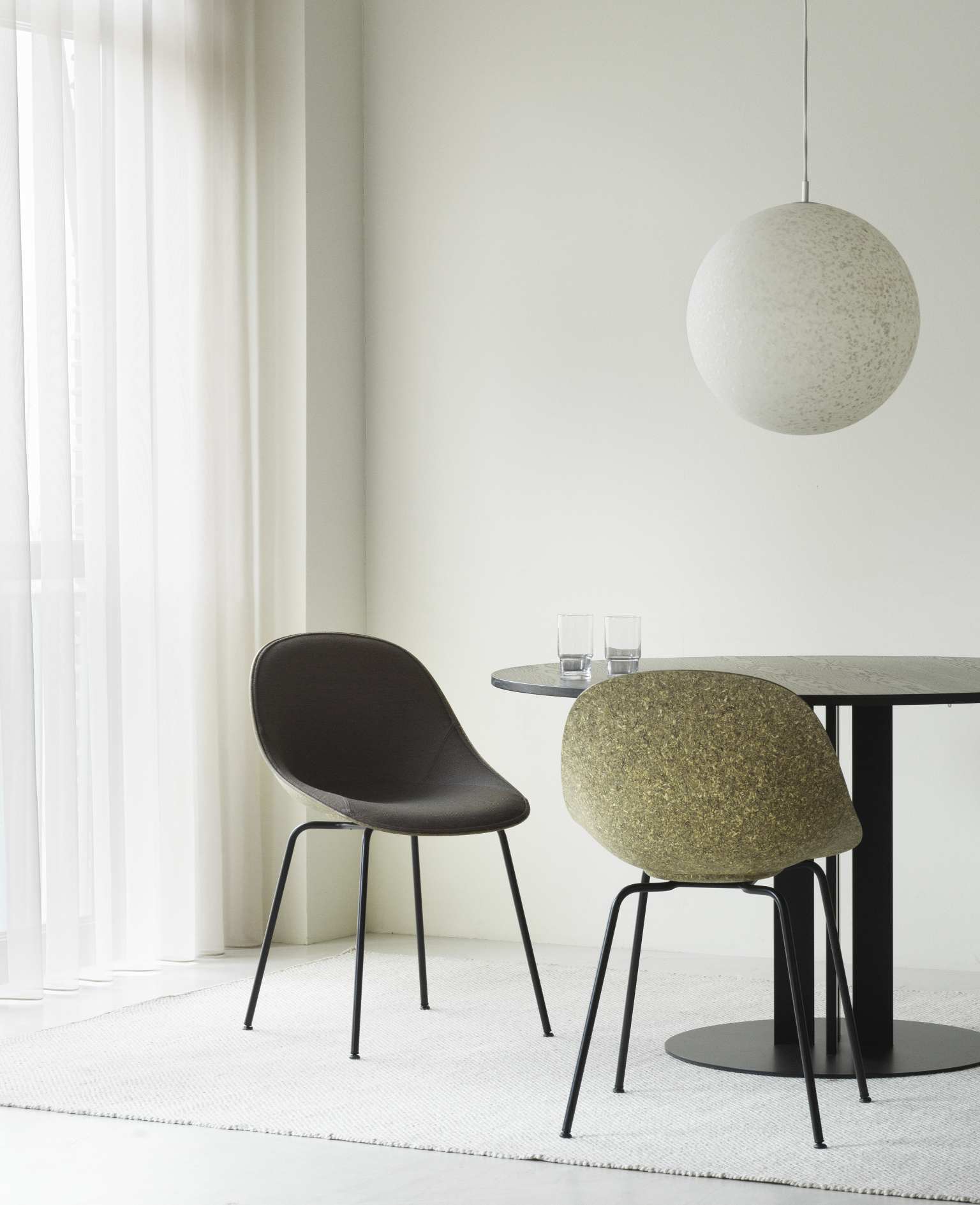 Zwei Normann Copenhagen Mat Chair Stühle in Grau und Grün am Esstisch mit Lampe.
