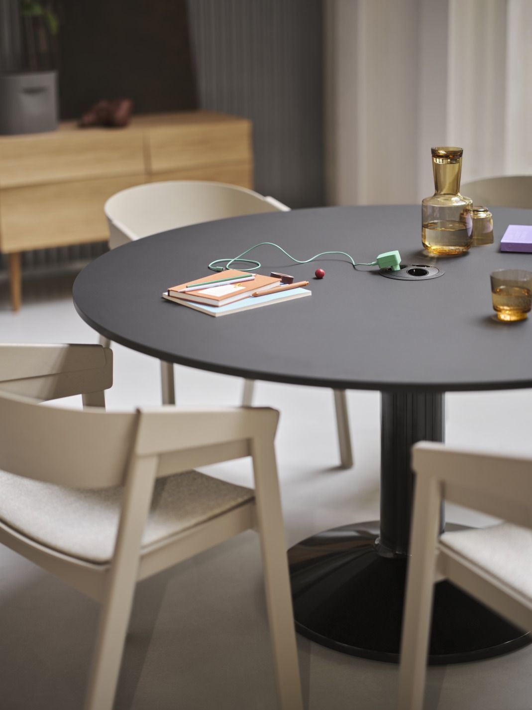 MIDST Table Esstisch von Muuto, runder Tisch mit schwarzer Tischplatte und beigen Stühlen im Esszimmer.
