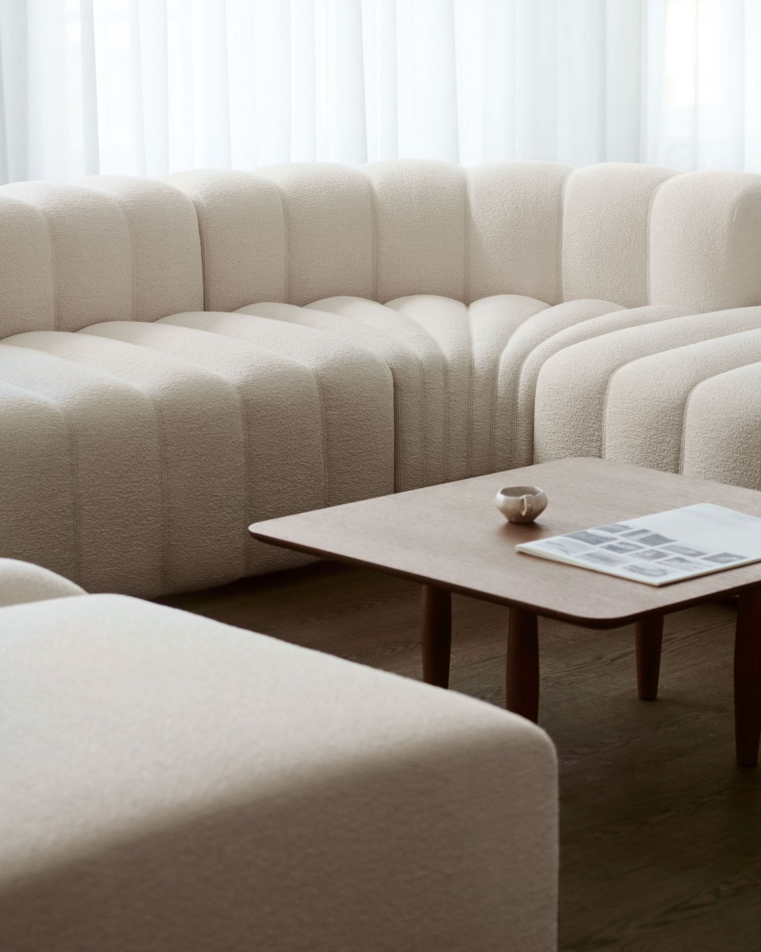 Oku Couchtisch von Norr11 aus Eiche, quadratisch, mit Magazin und Teetasse auf einem modernen Sofa.