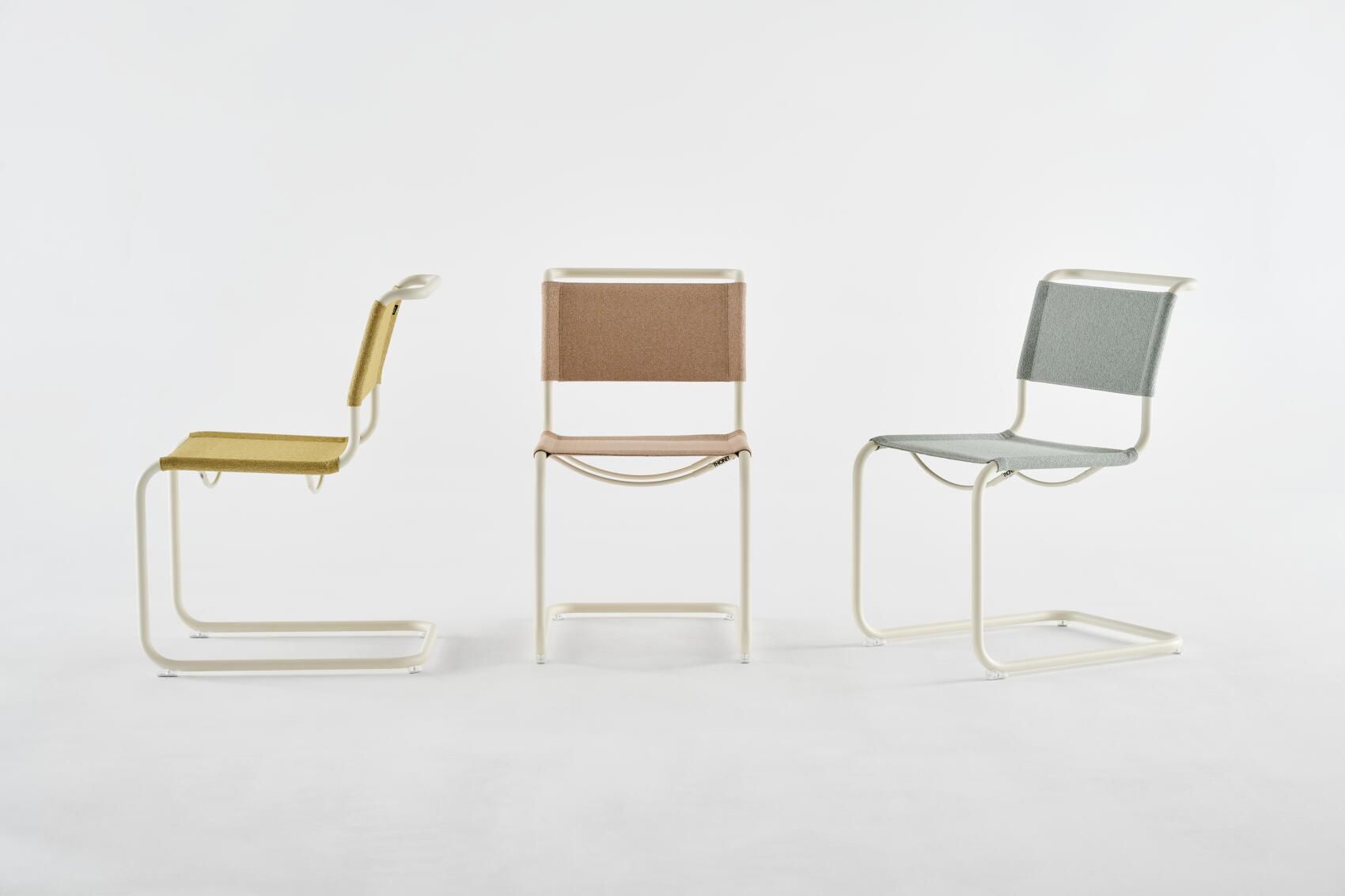 Drei Thonet S 33 V Freischwinger Stühle in Gelb, Braun und Grau vor weißem Hintergrund.