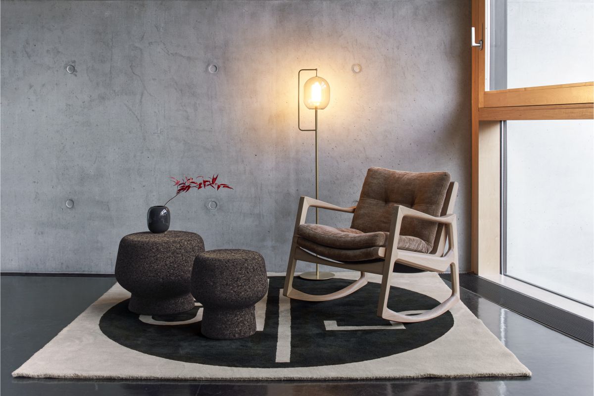 ClassiCon Corker Hocker als Beistelltisch, aus Kork, neben Sessel und Stehlampe auf Teppich.