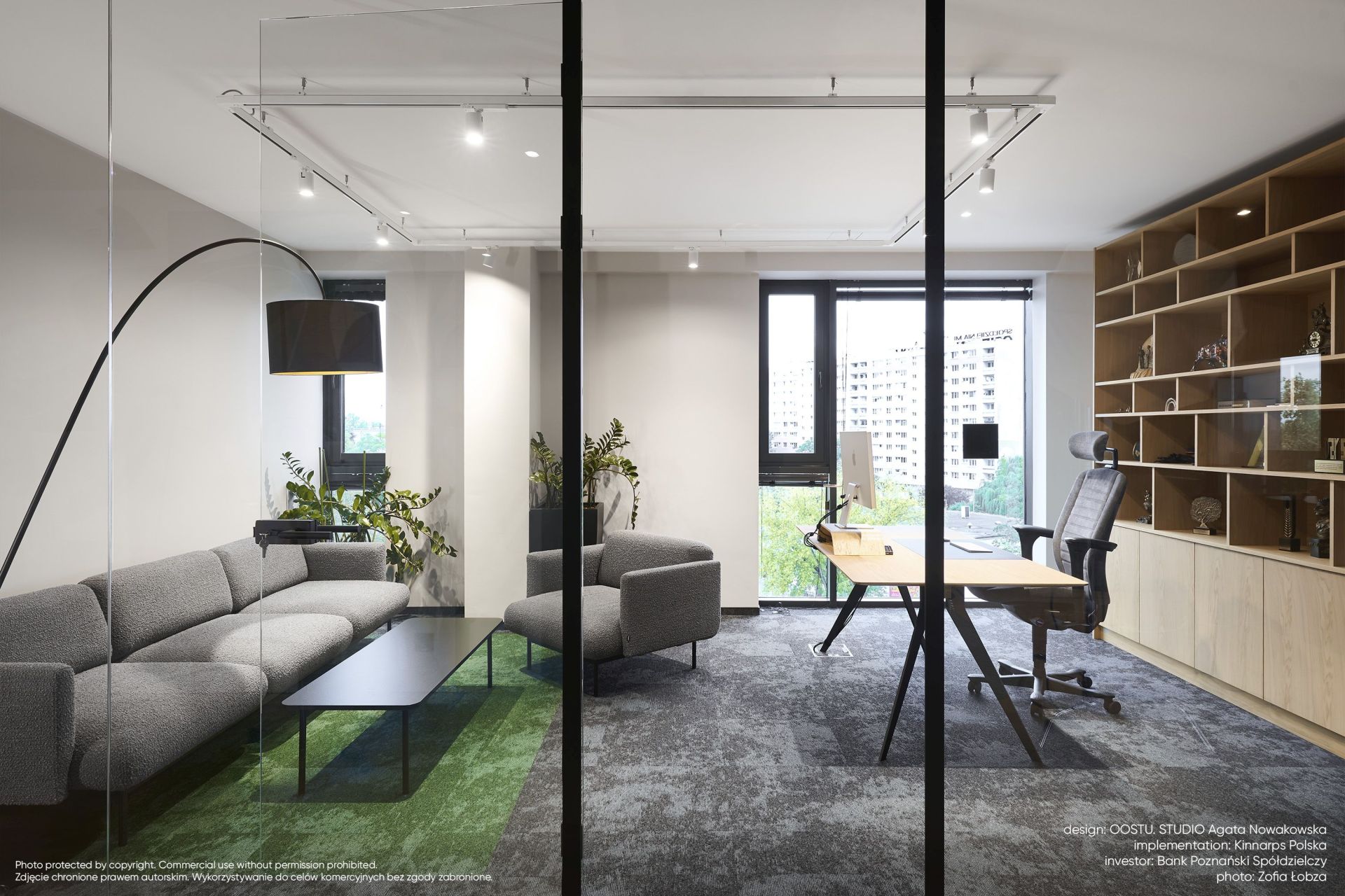 Büro-Lounge mit grauem fora FR 421 Sessel Bejot, Sofa, Schreibtisch und Regalen für moderne Büroeinrichtung.
