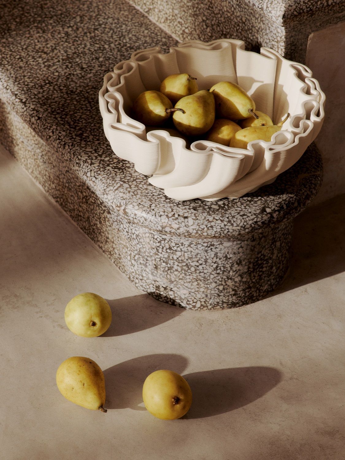 Off-white Dedali Bowl Schale von Ferm Living gefüllt mit gelben Birnen auf einer Steintreppe, moderne Tischdeko.