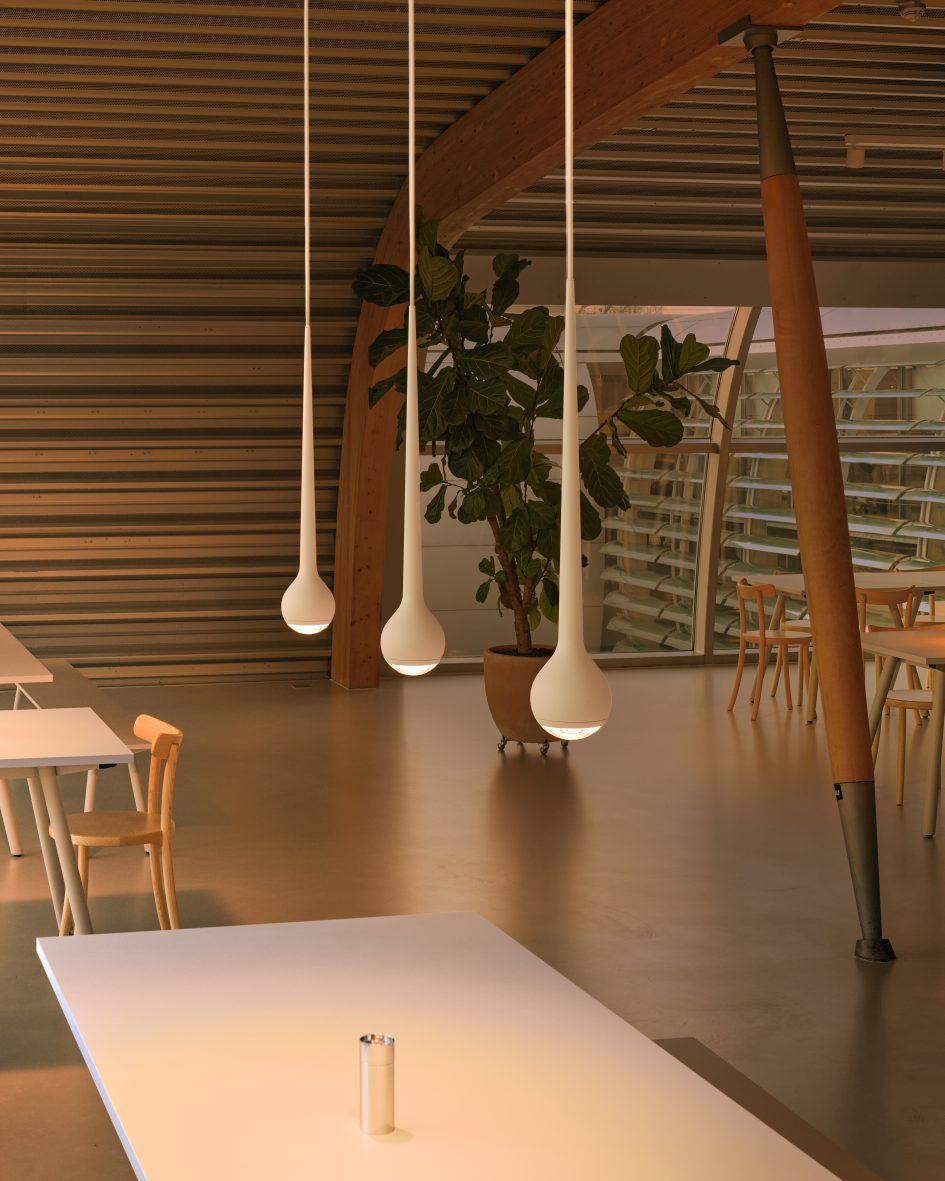Drei graue Falling Sun Pendelleuchten über Tischen in einem modernen Raum. Hängelampe für Esszimmer.