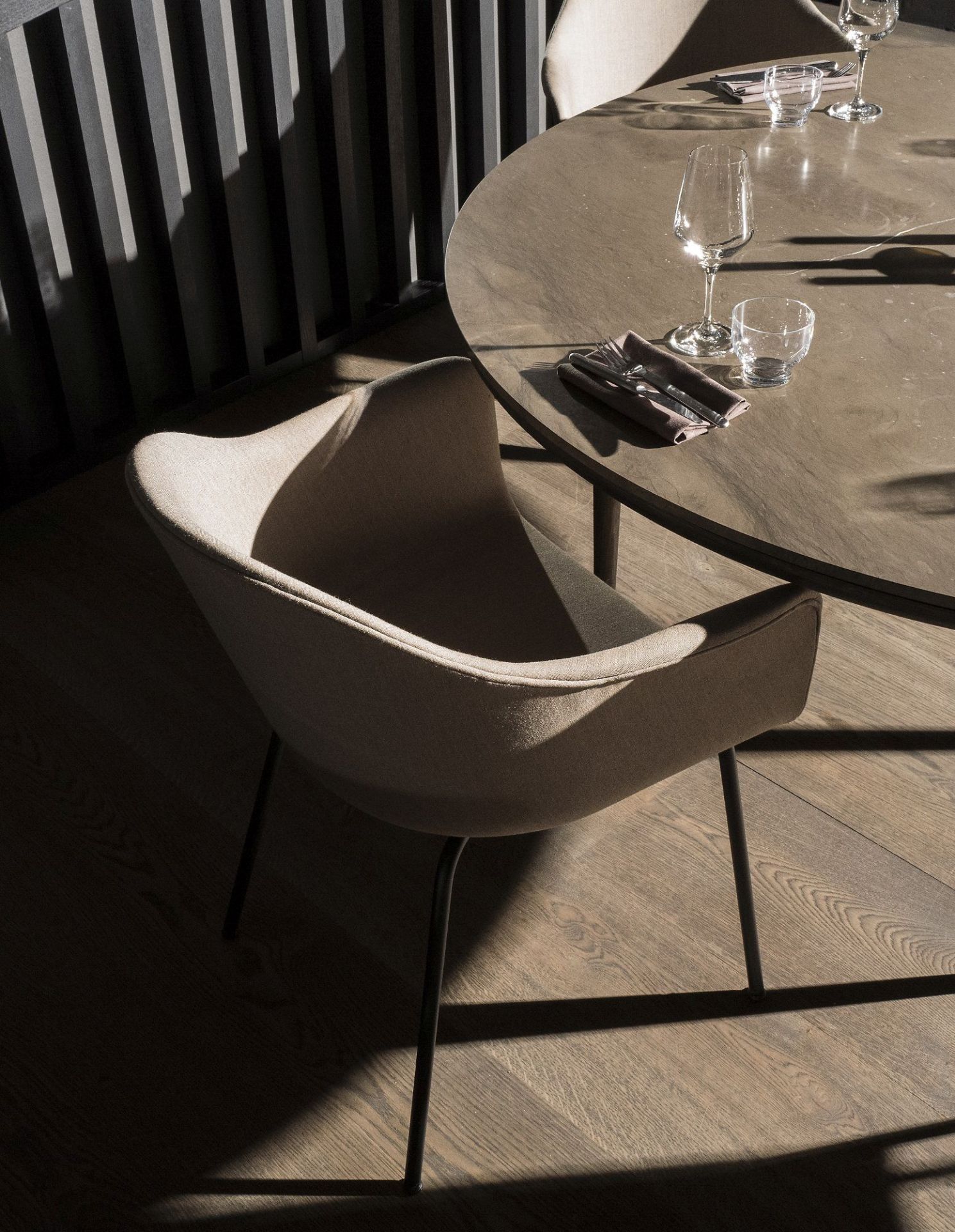 Beiger Harbour Dining Chair Stuhl von Audo Copenhagen am Esstisch mit Gläsern und Besteck.